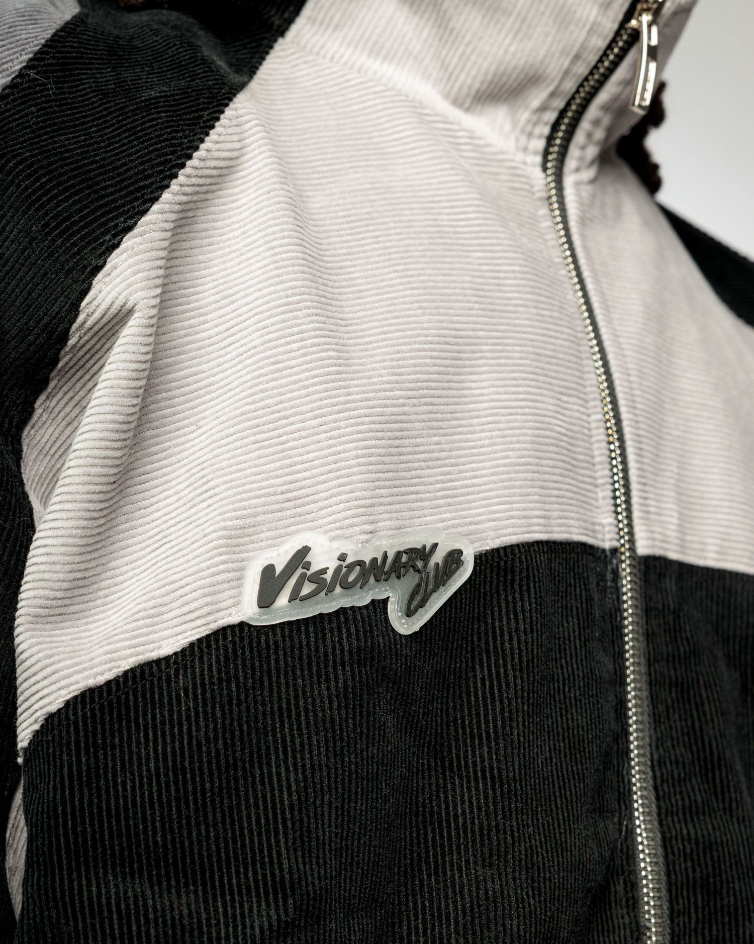 Close-up details of a black and white zip-up jacket with ribbed texture and contrasting panels.