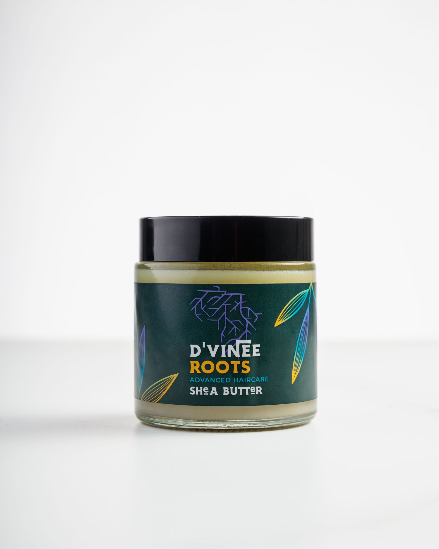 A jar of D'vinee Roots shea butter skincare product with dark green packaging and gold accents against a white background.