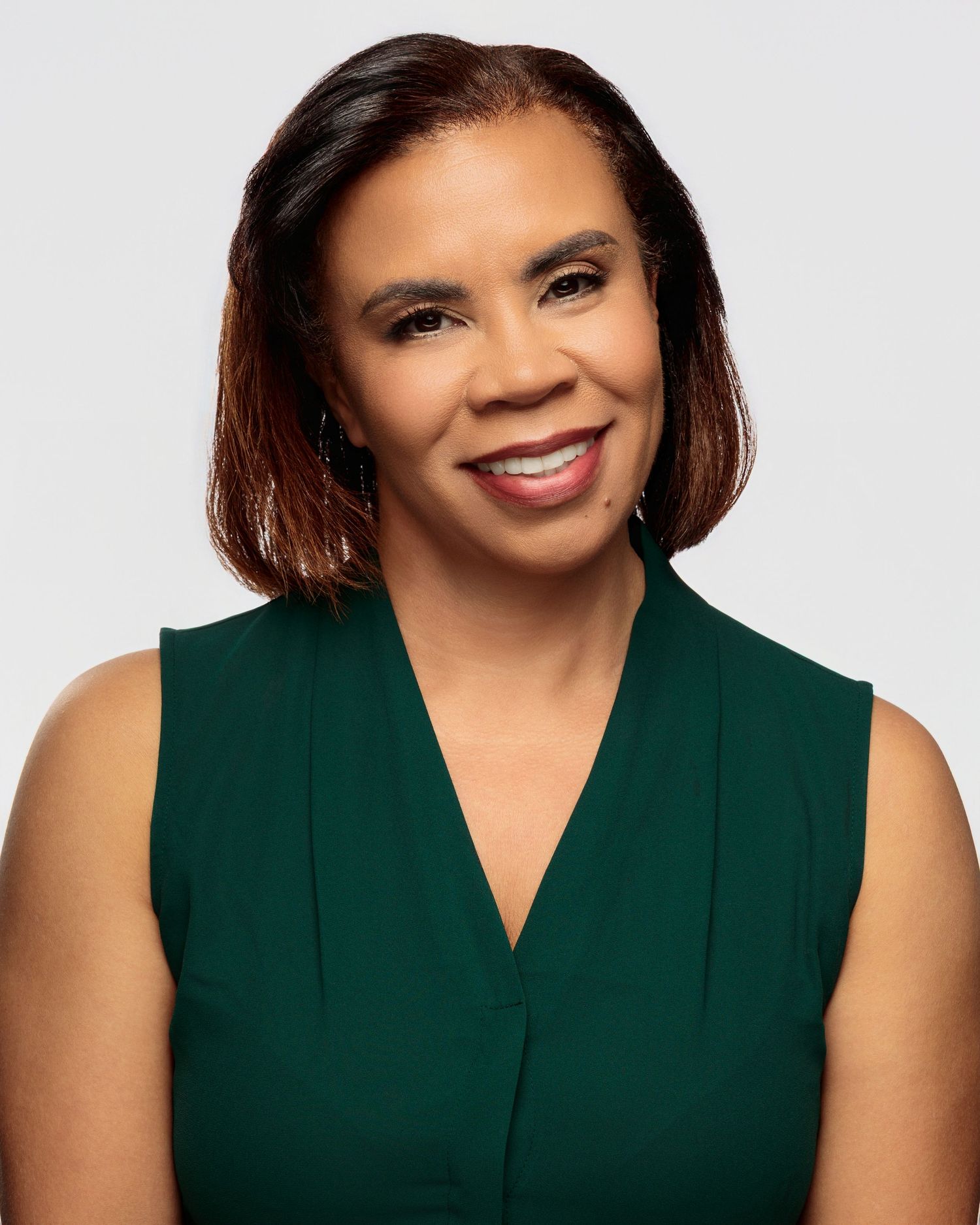 Professional headshot series of a person wearing a sleeveless dark green top against a light background.