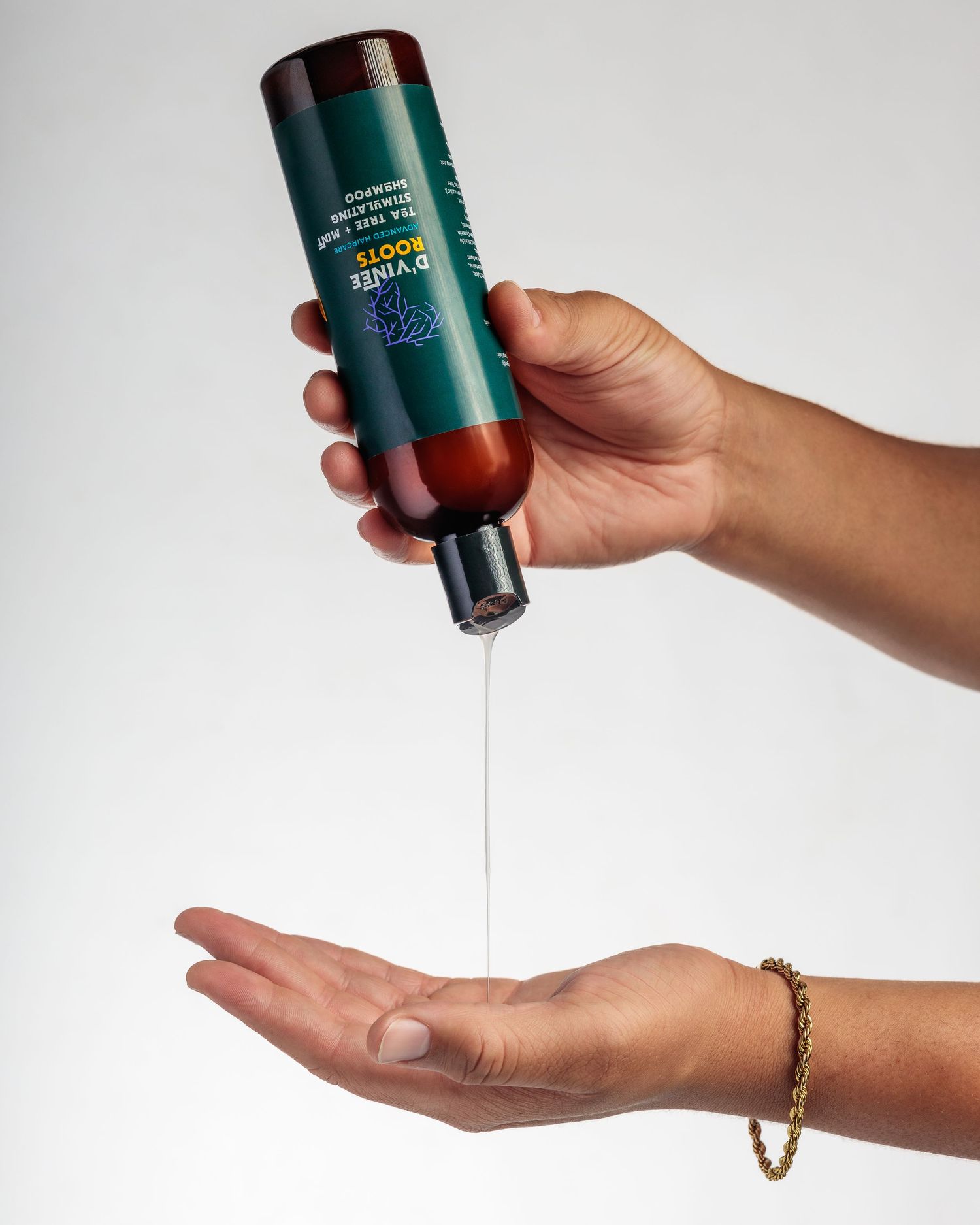 Hand holds a skincare product bottle and dispenses cream onto palm against white background.