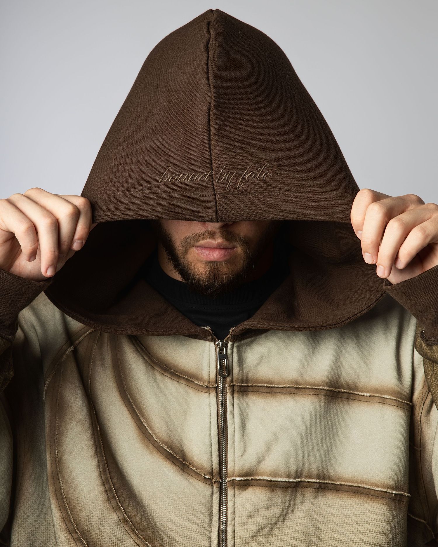 Close-up sequence showing a person pulling up a brown hooded jacket over a light-colored garment.