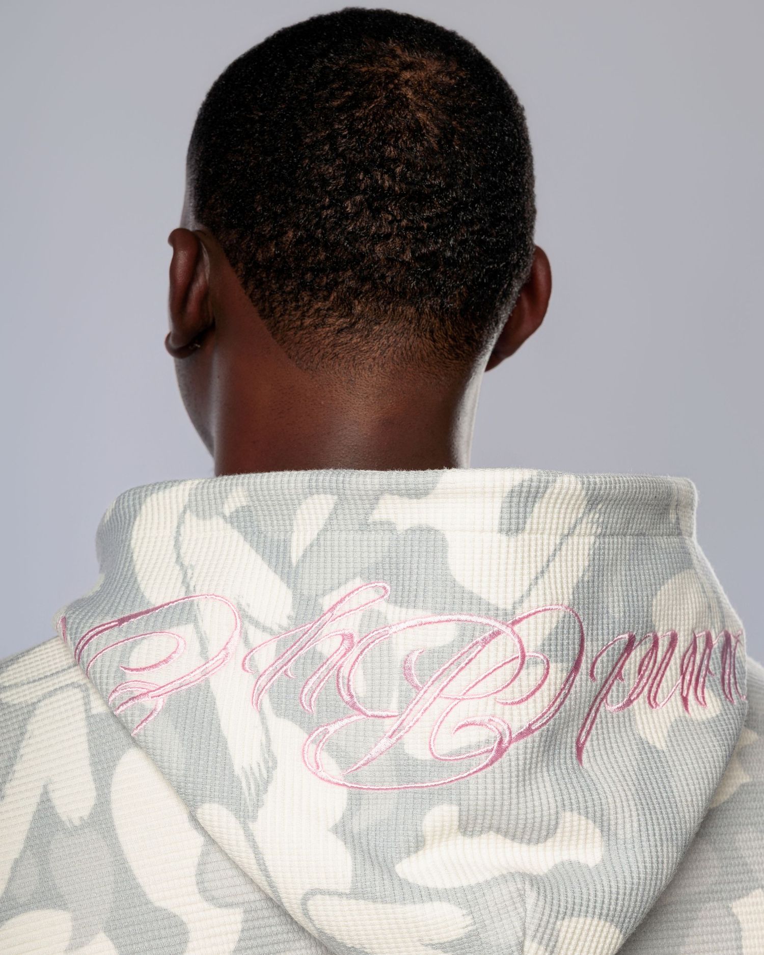 A white jacket with pink embroidered text details shown from different angles.