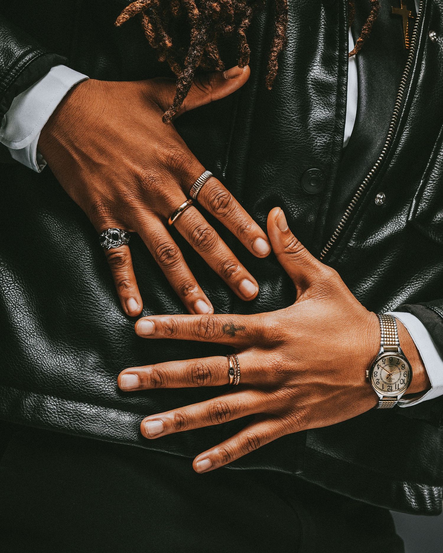 Close-up view of hands with rings resting on black leather upholstery showing different angles and positions.