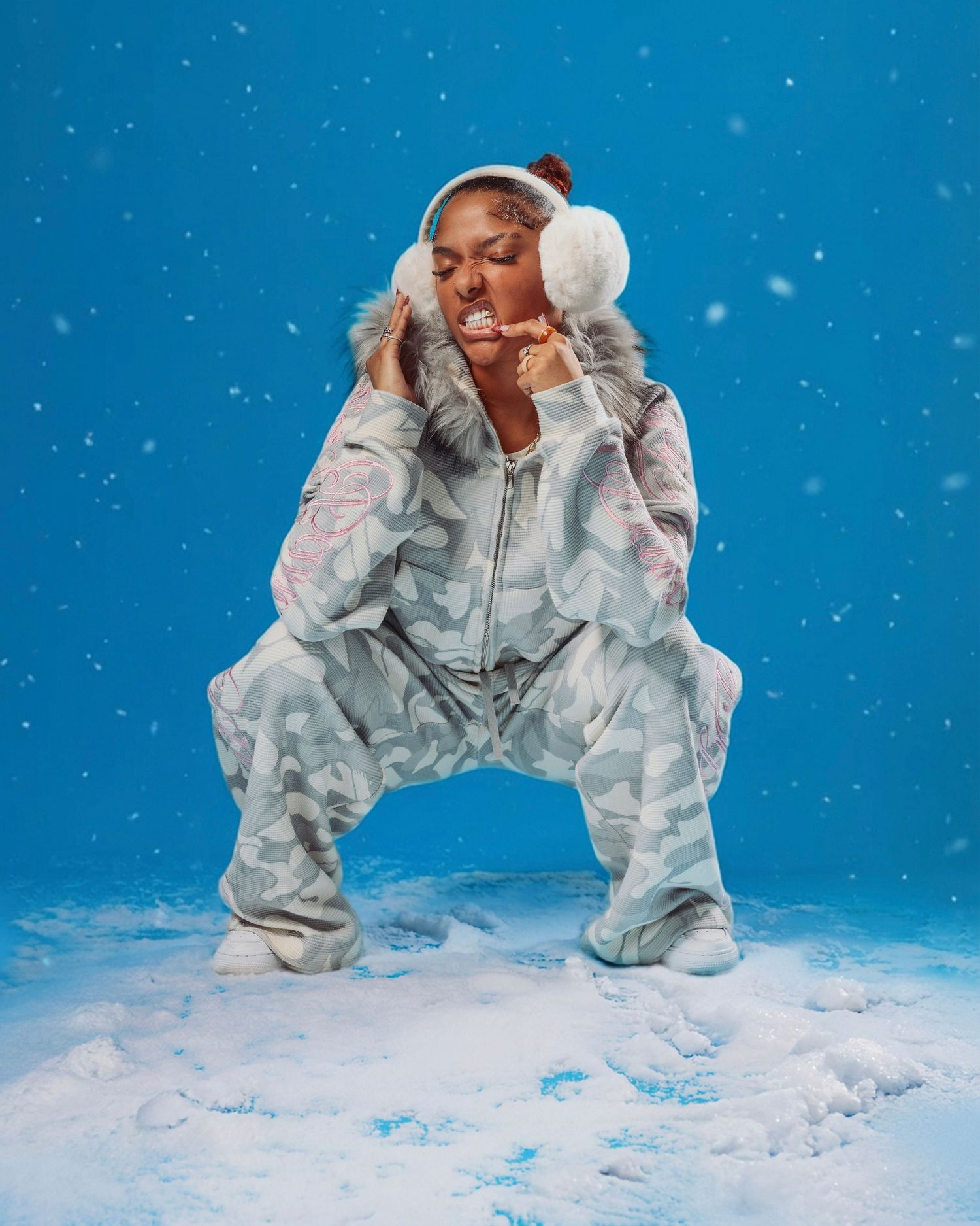 A figure in white winter clothing performs dynamic poses against a snowy blue backdrop with falling snow.