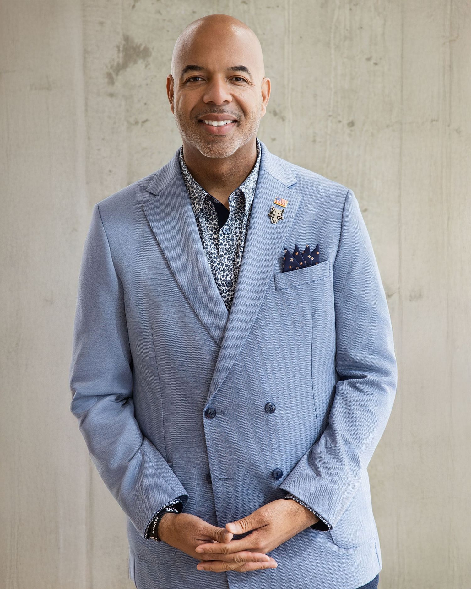 A person wearing a light blue suit jacket poses against a neutral background in a professional portrait series.
