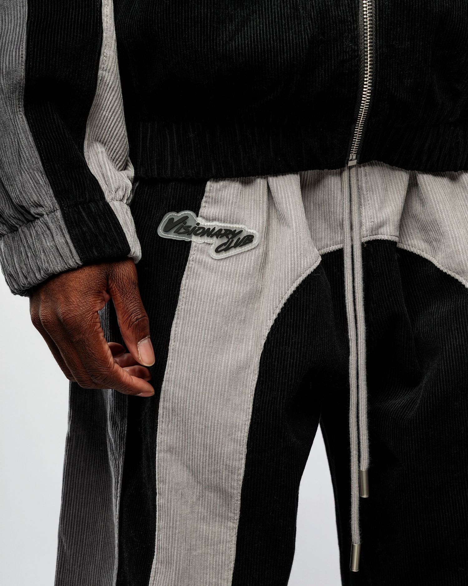 Close-up view of a person wearing black and white striped tracksuit pants with drawstring detail.