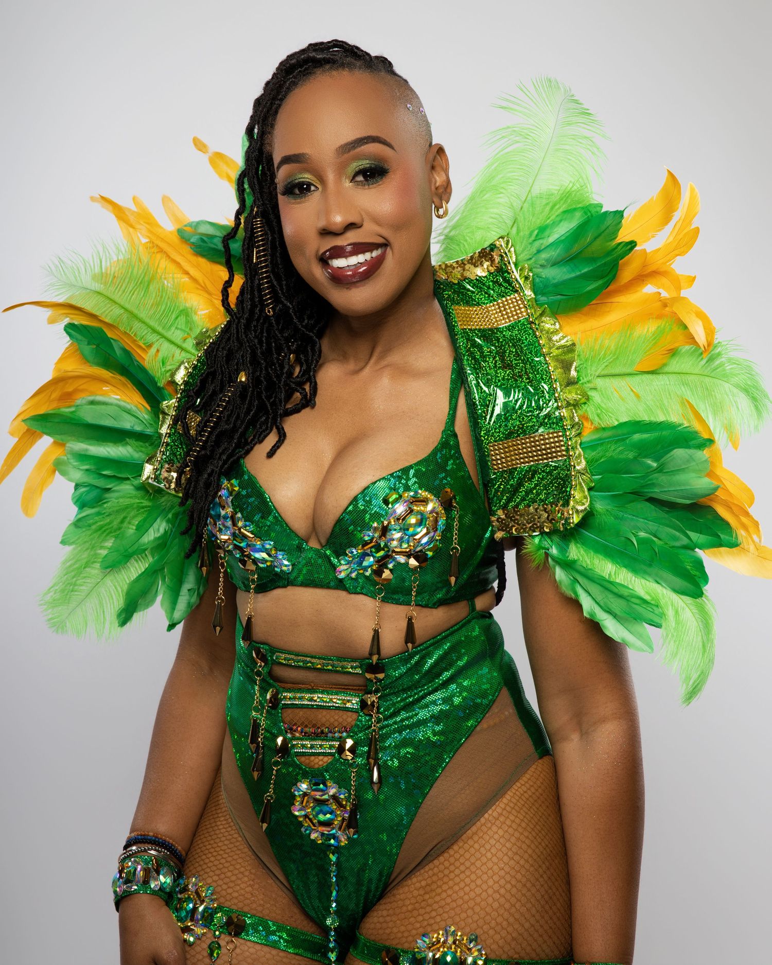 Close-up of carnival dancer in emerald green sequined costume with feathered wings.