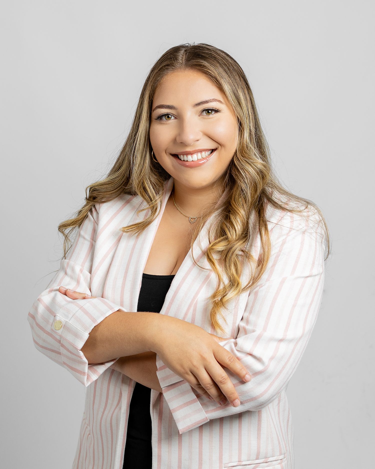 Professional headshot of someone in a white pinstriped blazer and black top against a light gray background.