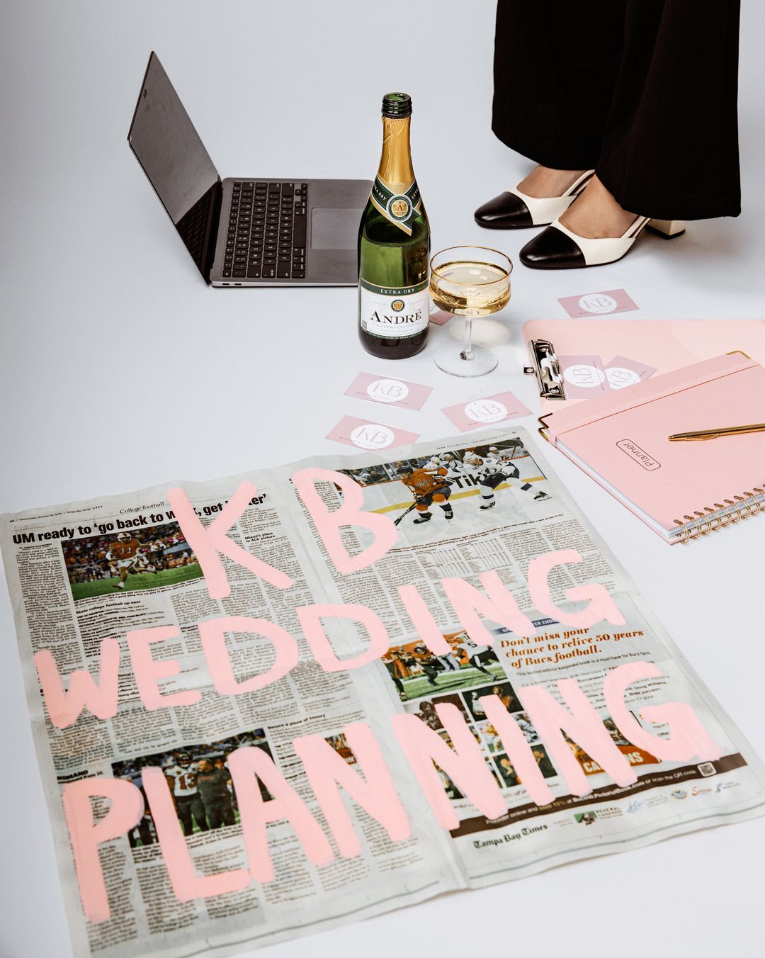 Wedding planning layout with newspaper articles and pink highlighter markings spread across a white surface.