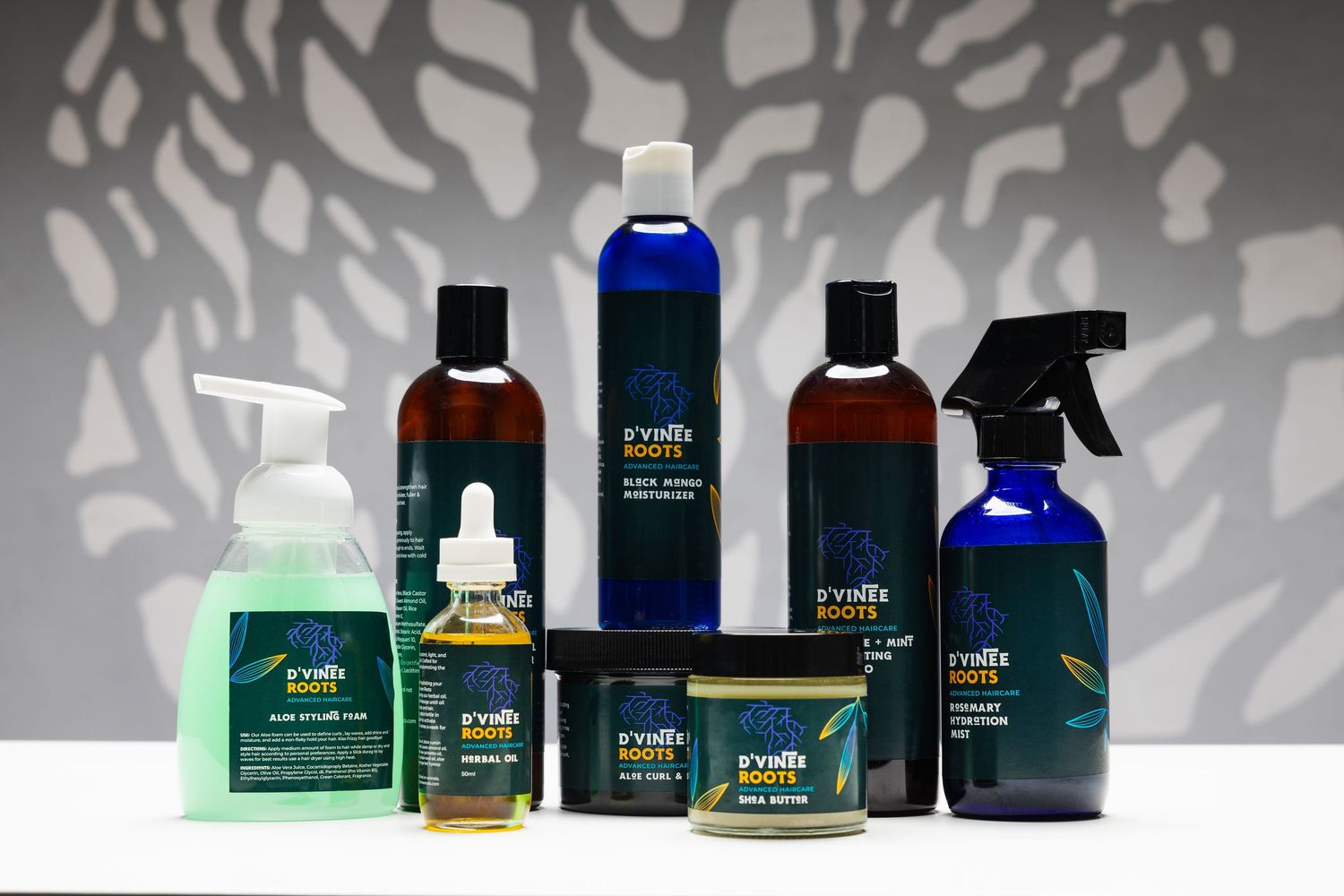 Collection of Earth Luxe beauty and skincare products in dark glass bottles arranged against a gray background.