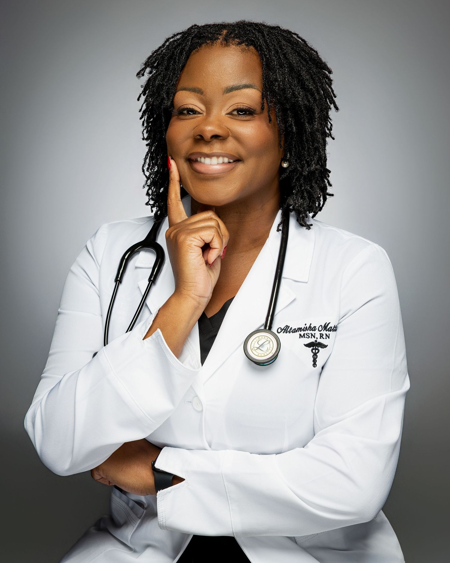 Medical professional in white coat smiles confidently in studio portrait series against gray background.