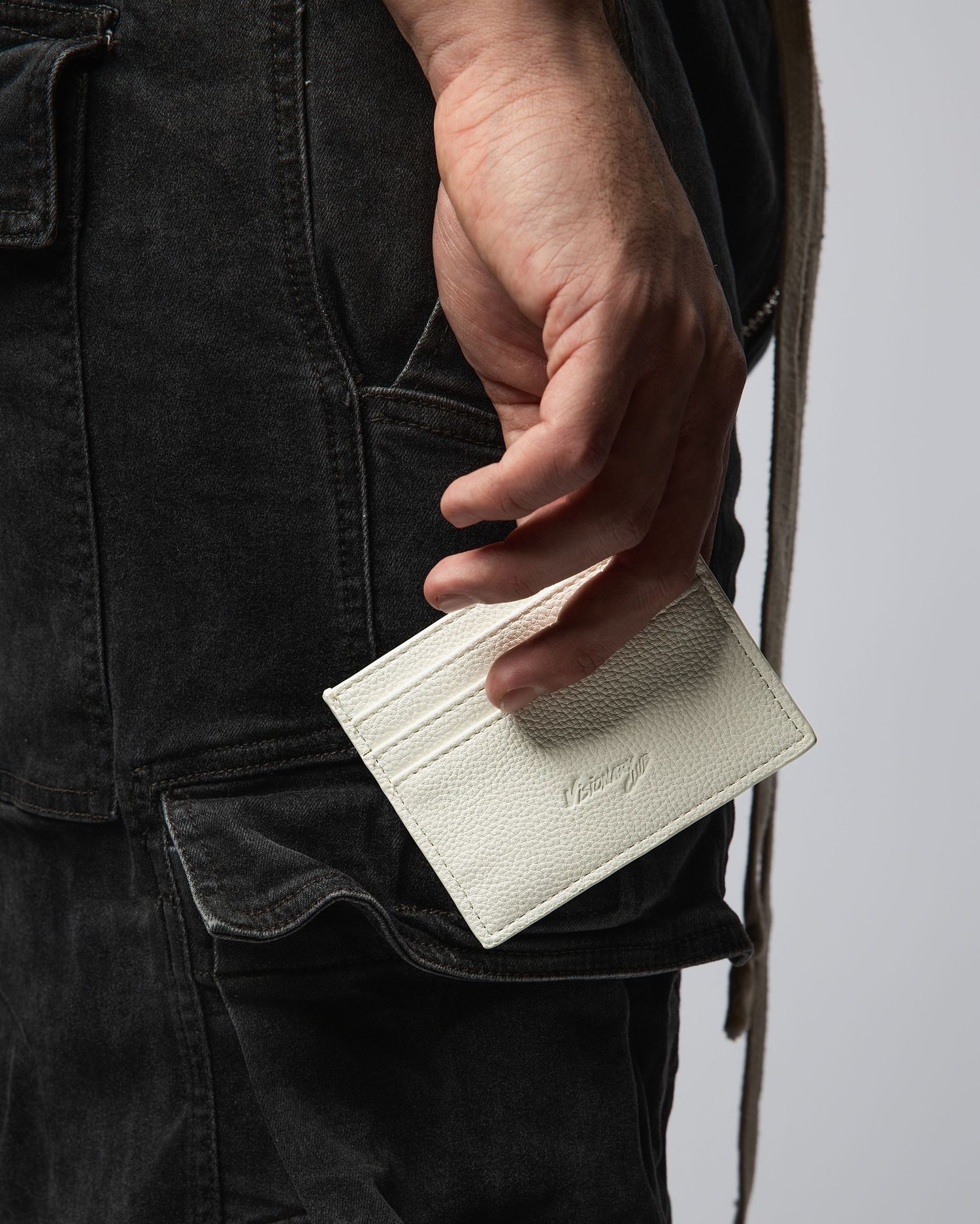 Hand demonstrating how to slip a white card into a black denim jeans pocket.