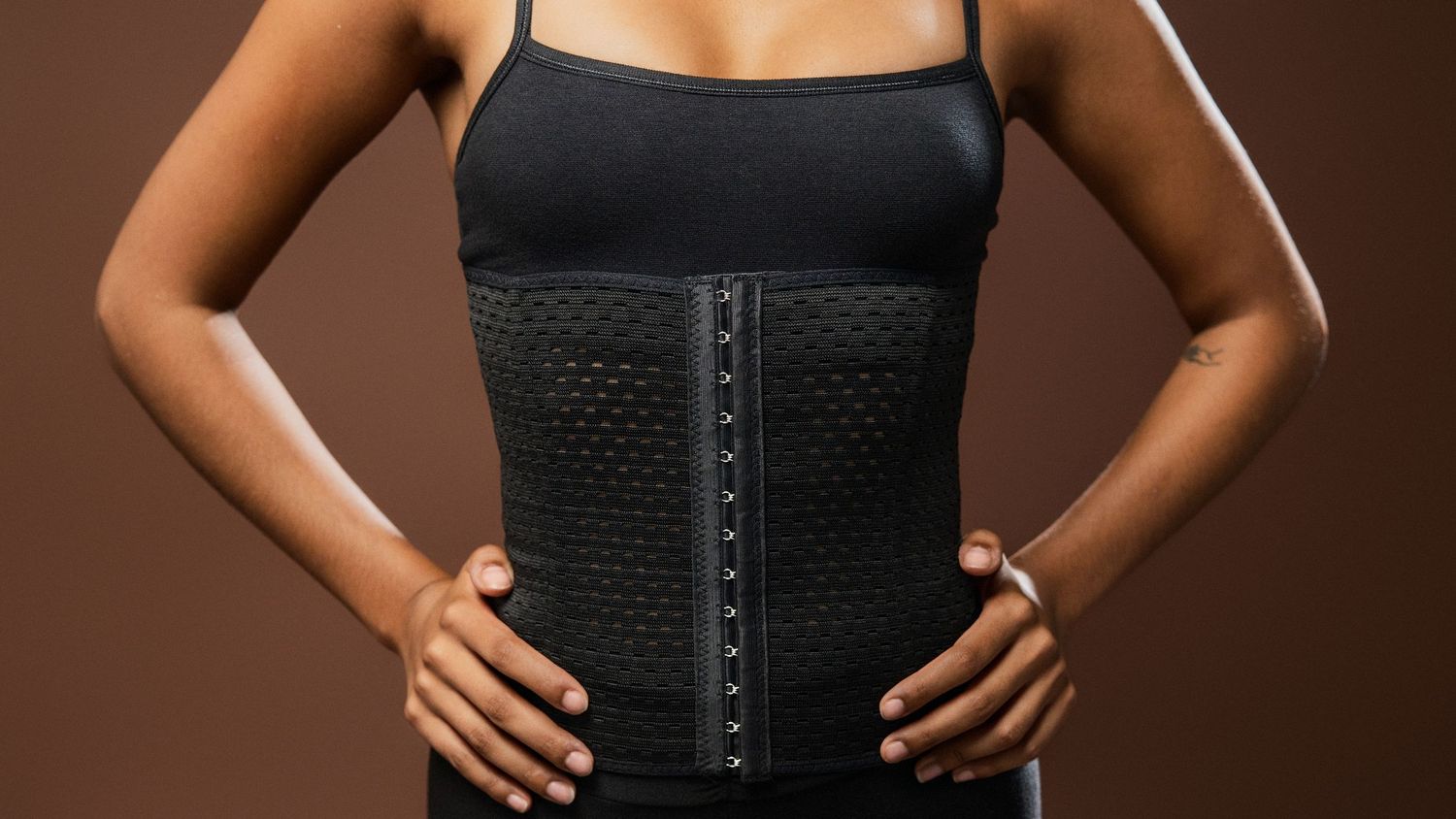 Detail shots of black waist trainer with hook closures against brown background.