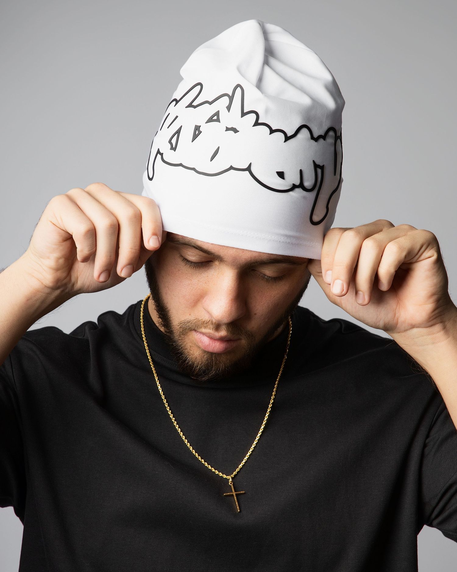 A sequence of photos showing someone adjusting a white beanie hat while wearing a black sweater and gold chain necklace.
