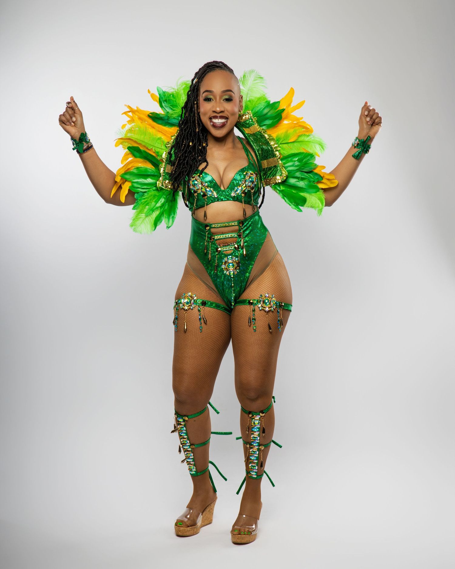 Carnival dancer in vibrant green and yellow feathered costume against white background.