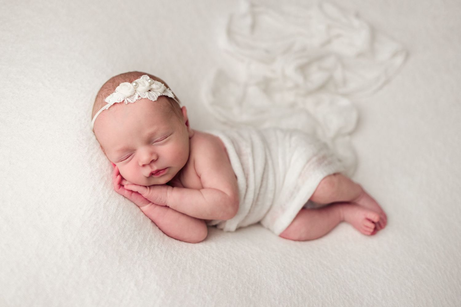 Sleeping newborn baby wrapped in soft white fabric lying on white blanket in artistic collage of poses.