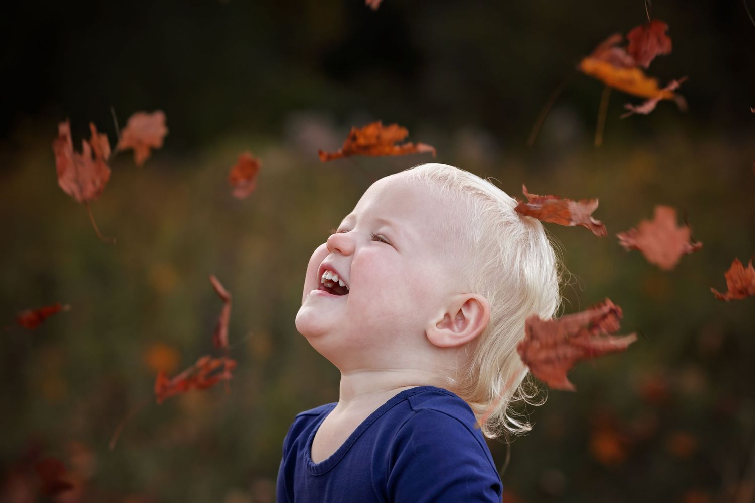 A joyful moment captured during autumn as colorful leaves fall in the background.