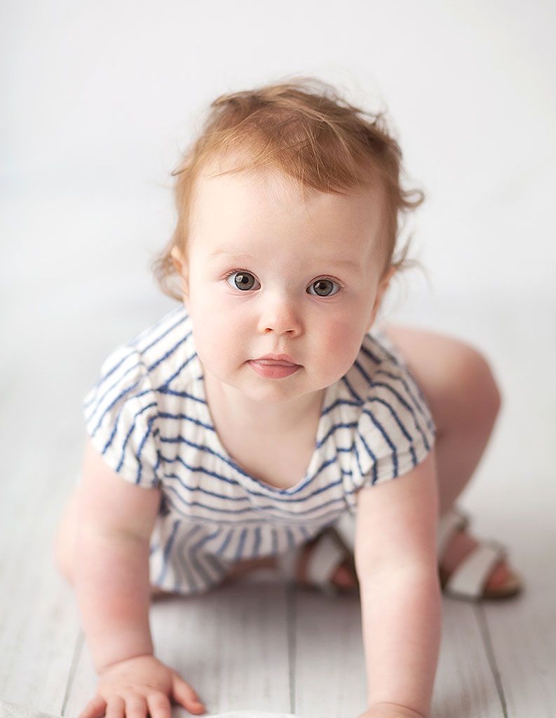 Baby in striped outfit crawls across white wooden floor in sequence of progressive movement shots.