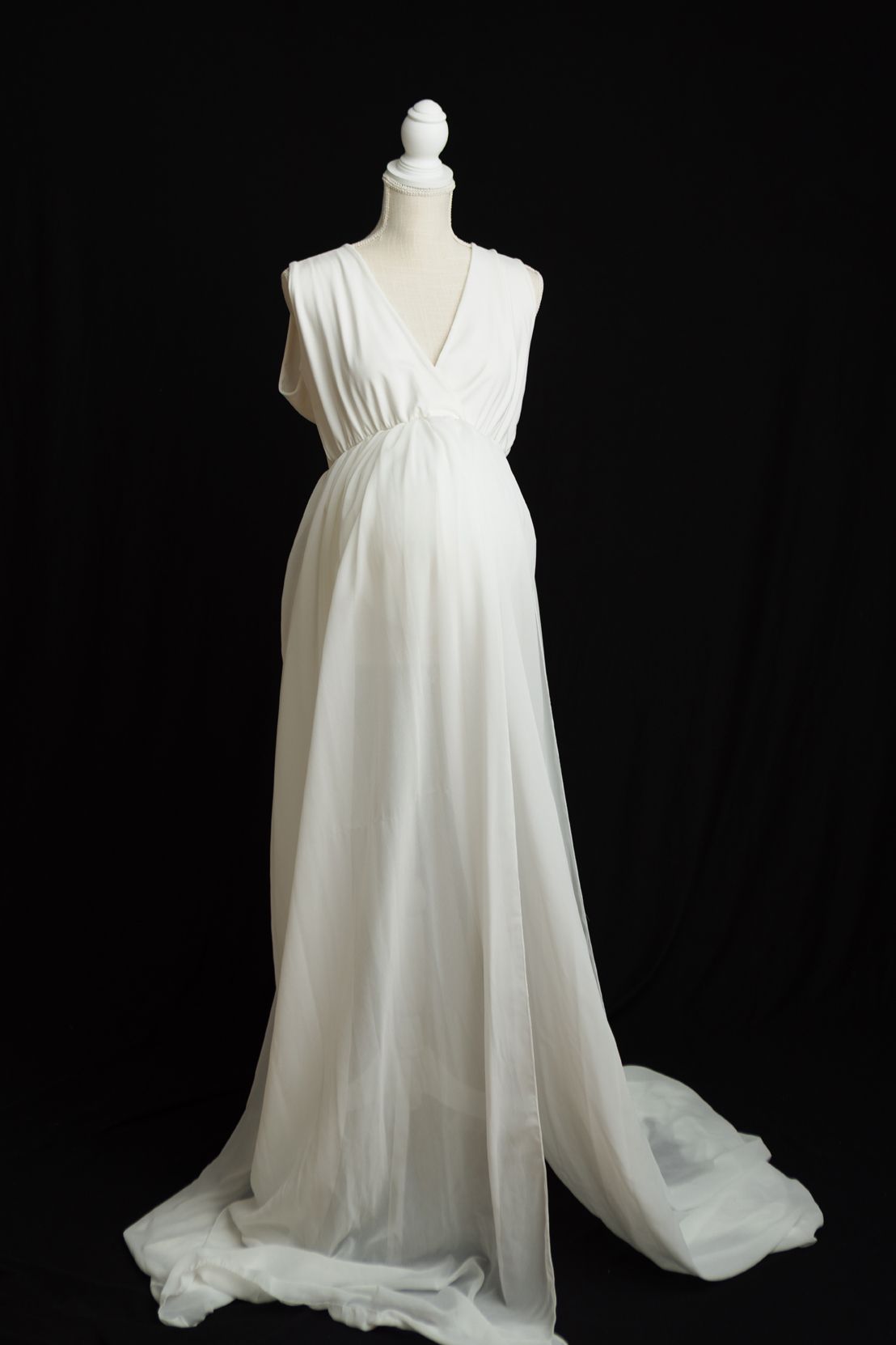 White flowy nightgown with delicate straps and loose silhouette displayed against dark background.