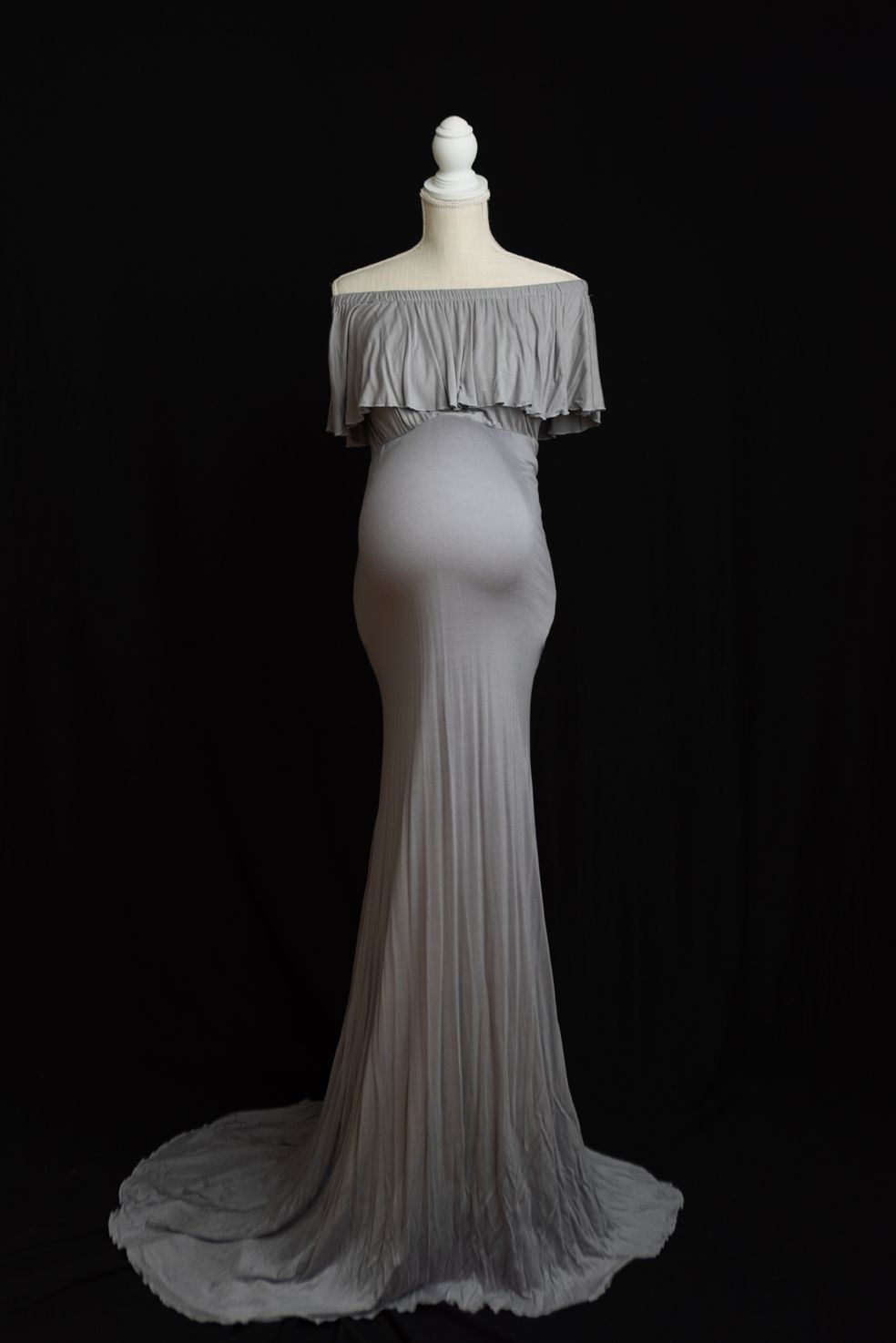 Off-shoulder maternity gown in light gray chiffon with flowing train photographed in sequence on black background.