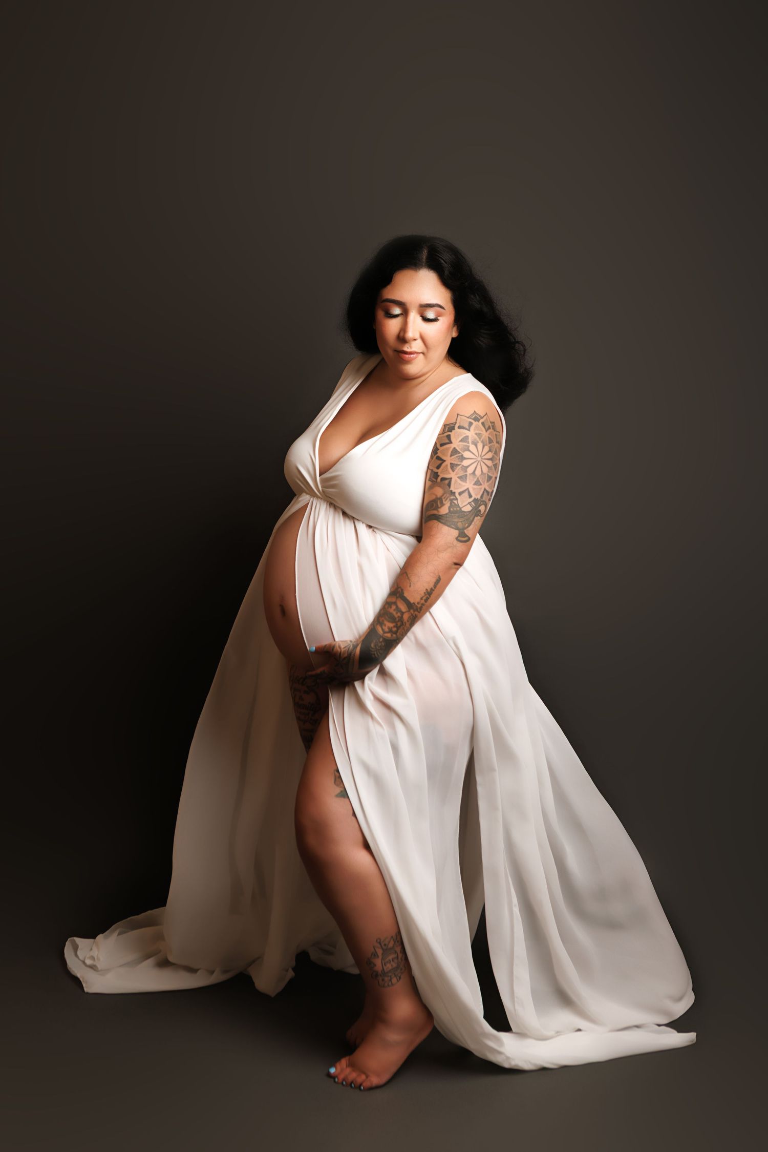 Artistic boudoir photography series showing figure in flowing white fabric against dark background creating dramatic contrast.