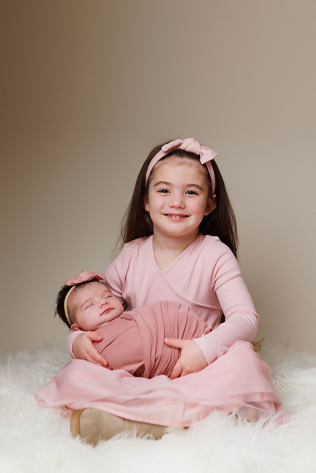 A series of four connected photos showing a child in a pink dress lying on a white fluffy surface.