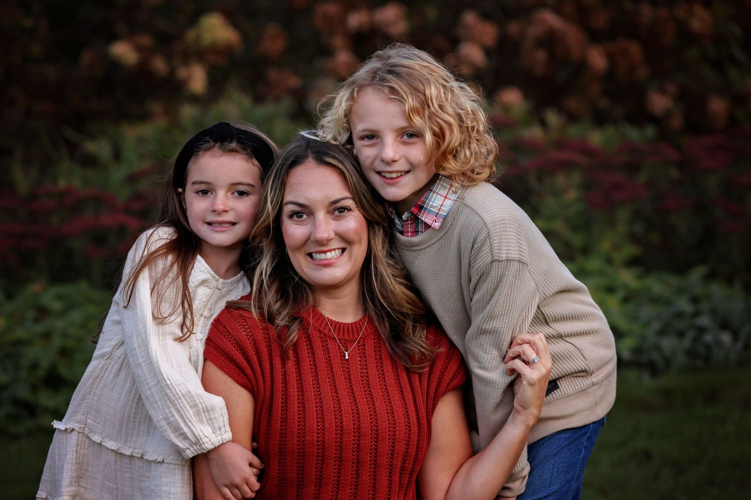 A family poses together outdoors in coordinated autumn outfits during a fall photo session.