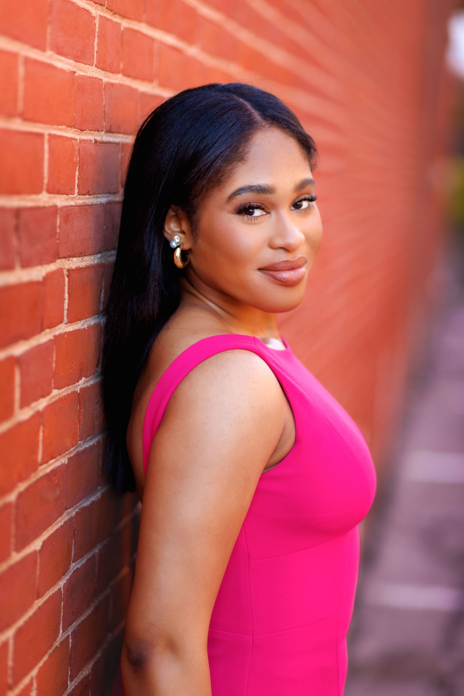 Salem New Hampshire high school senior in a bright pink dress against a red brick wall