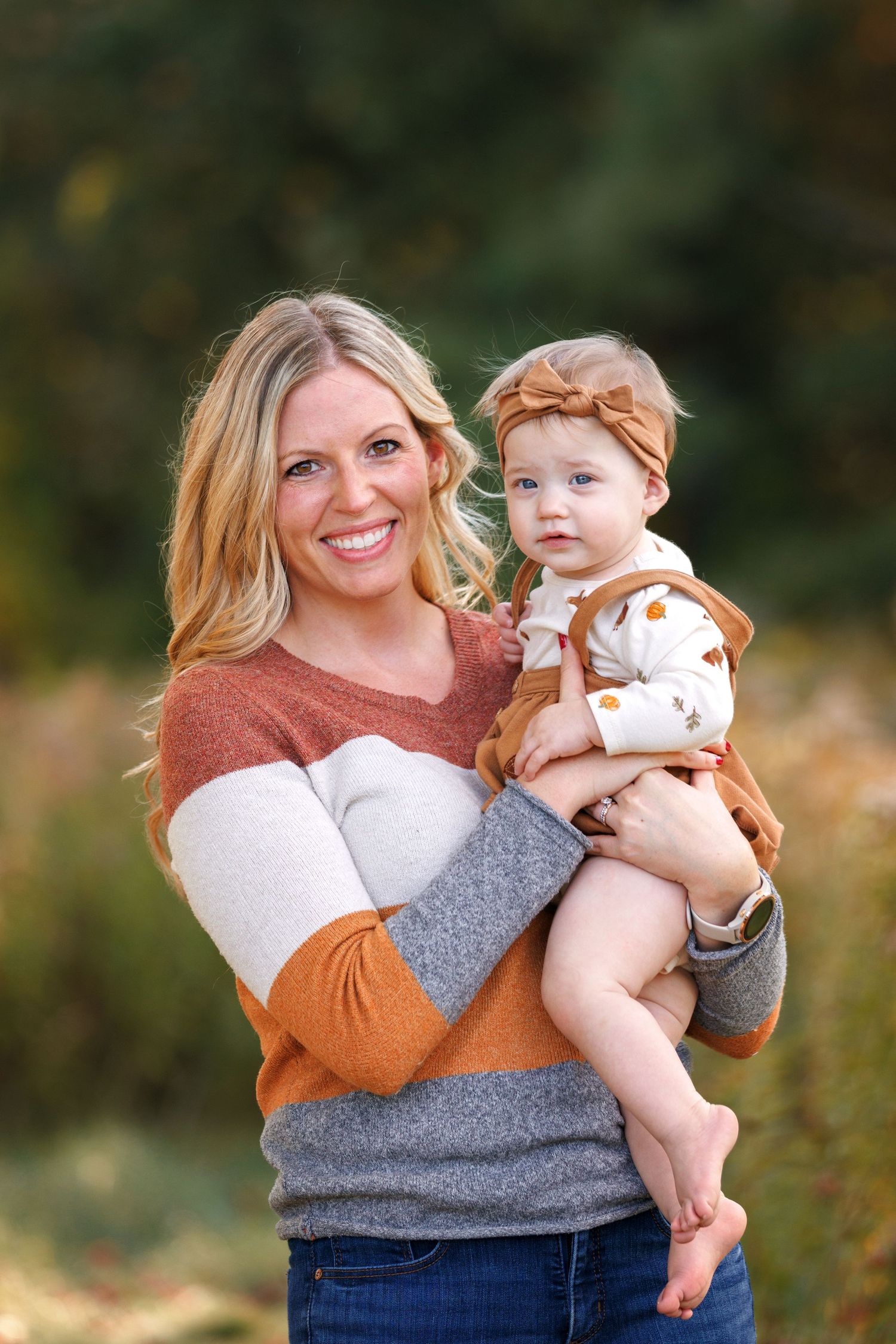 Parent in colorblock sweater holds toddler against autumn outdoor backdrop in progressive photo series.