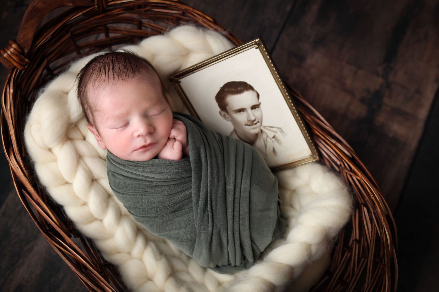 A newborn baby sleeps peacefully in a brown woven basket lined with soft cream-colored fabric.
