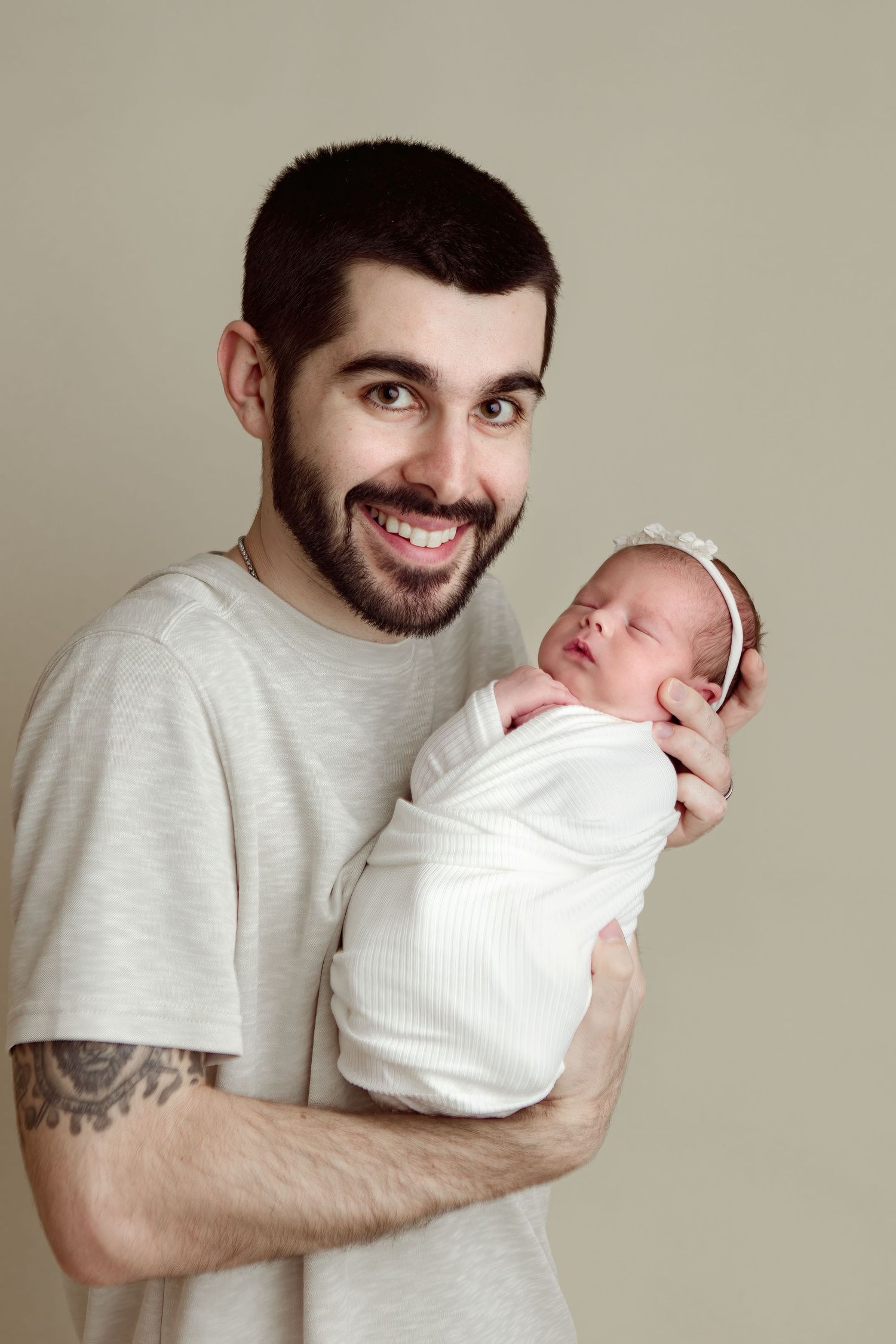 A series of tender moments captured between a parent in a gray shirt holding a swaddled newborn baby in white.