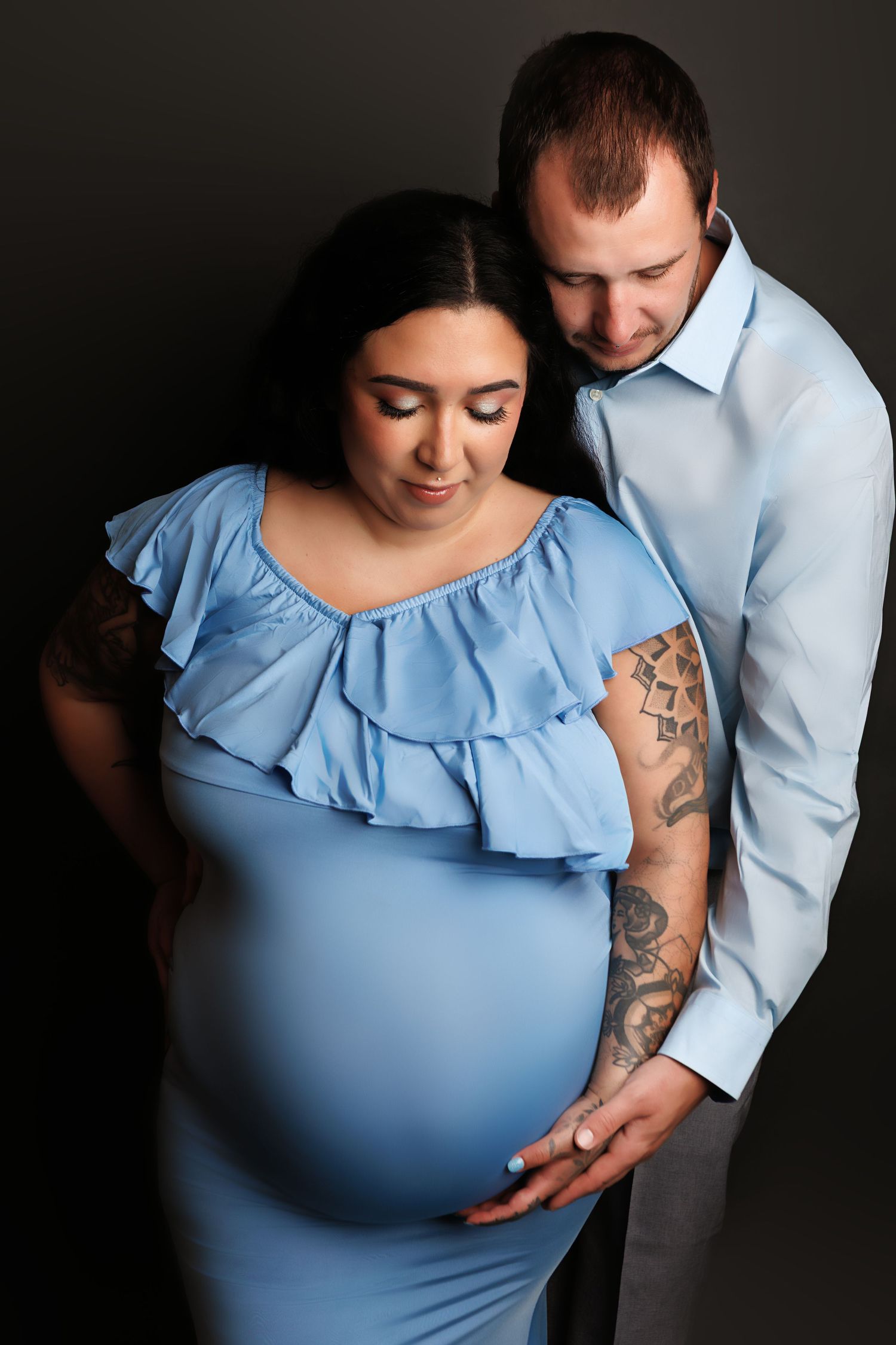 A series of intimate maternity photos showing a couple in light blue clothing against a dark background.