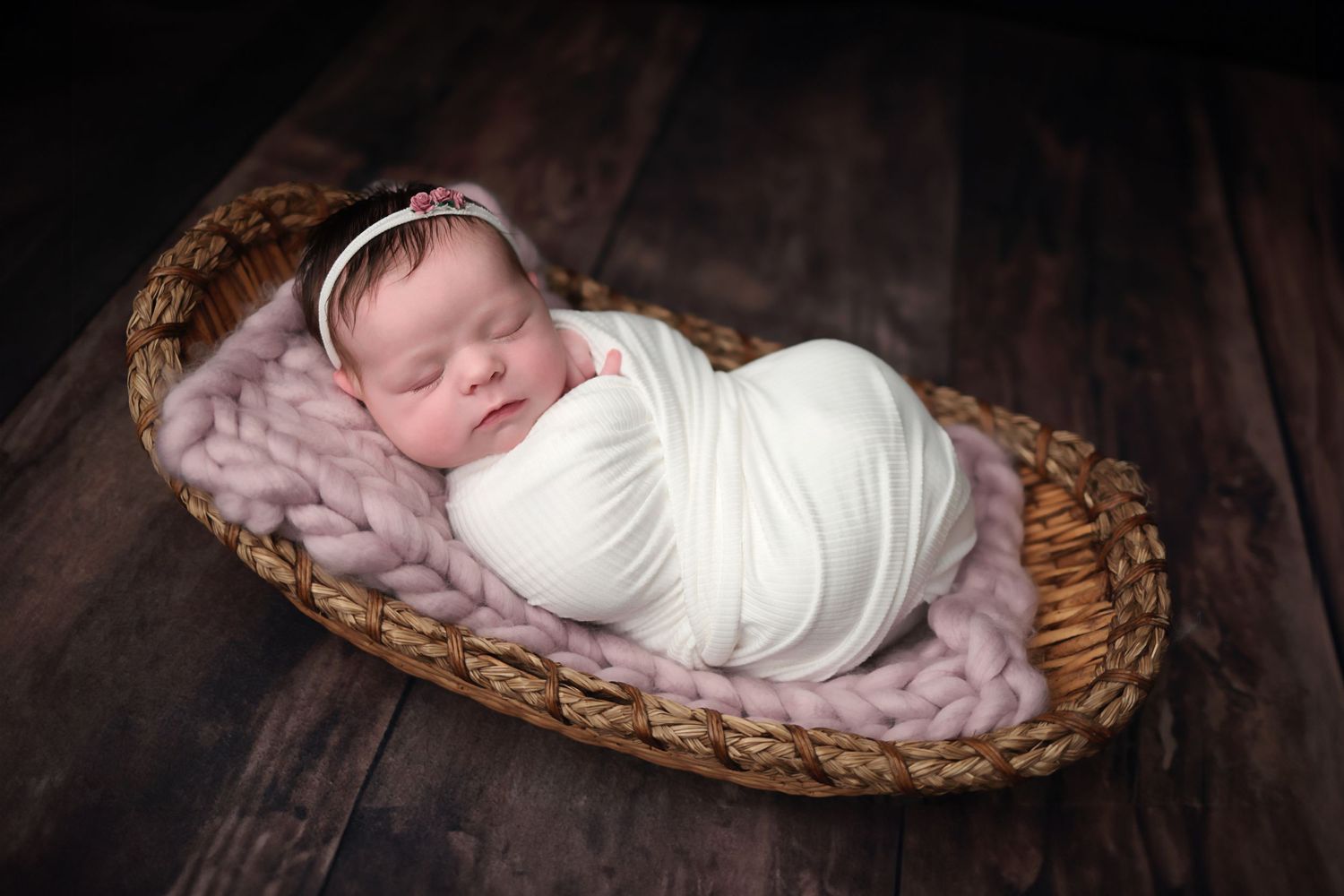 A series of photos showing a sleeping newborn wrapped in white swaddling blanket inside a woven basket.