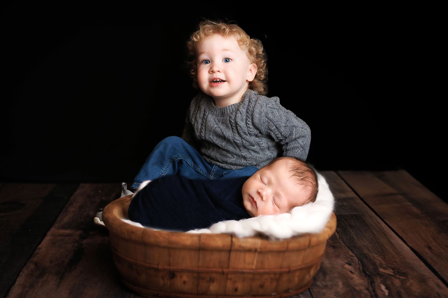 Seven professional baby portraits in rustic wooden settings showcase different poses and expressions.