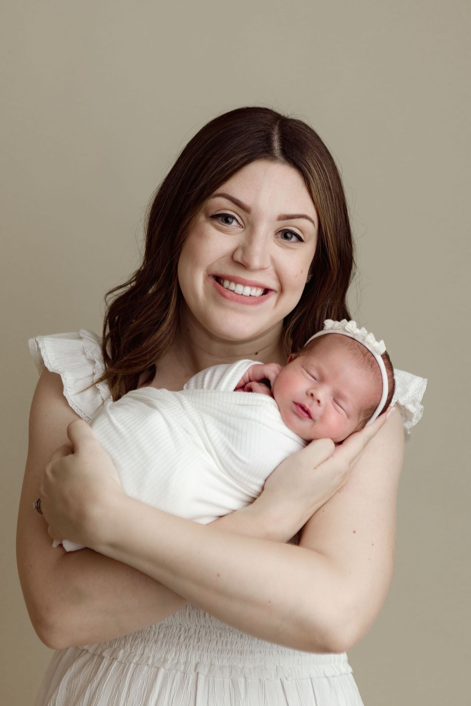 A series of five connected photos shows a woman in white holding and snuggling with a sleeping newborn baby.
