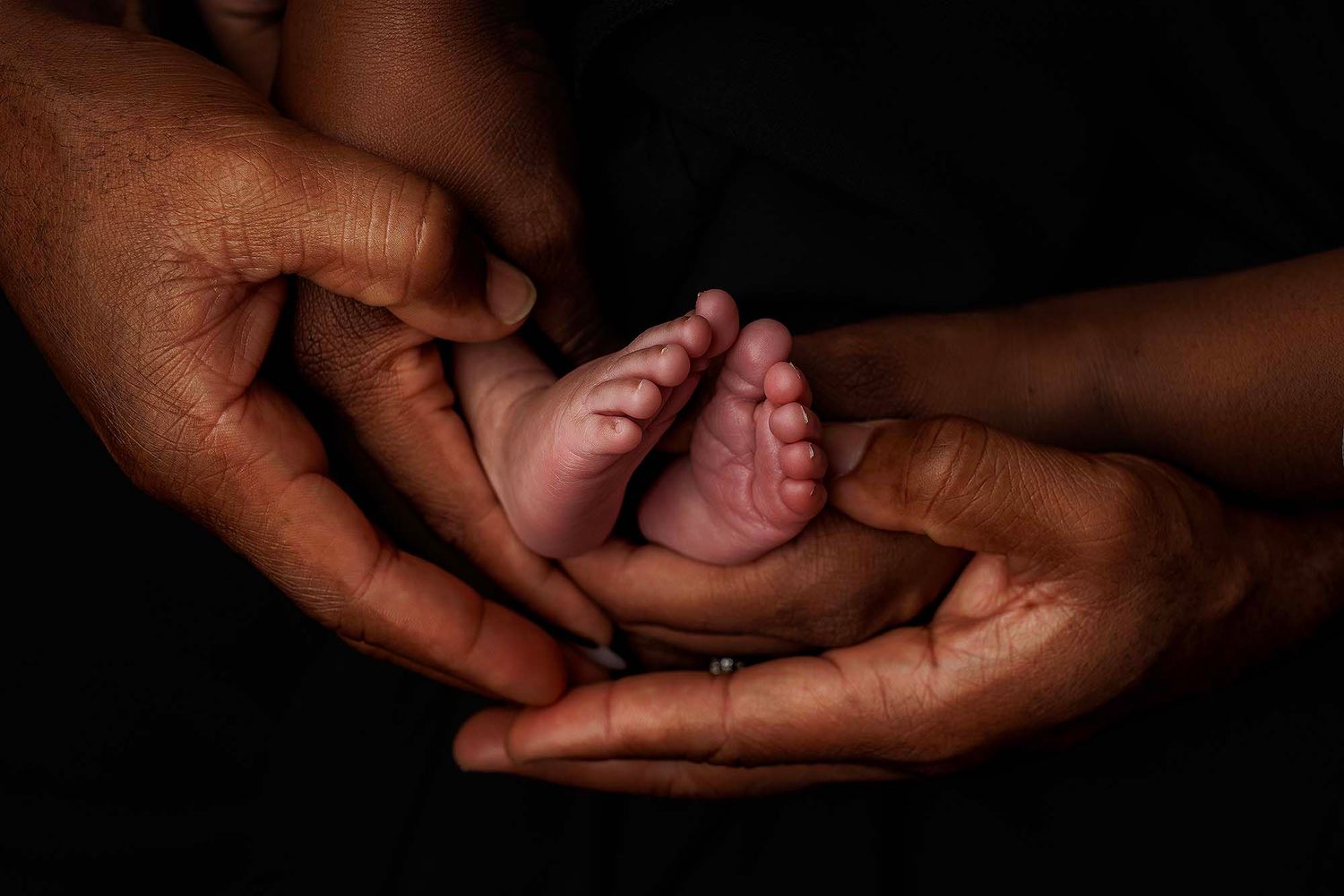 Black and white series showing gentle hands cradling a sleeping newborn.