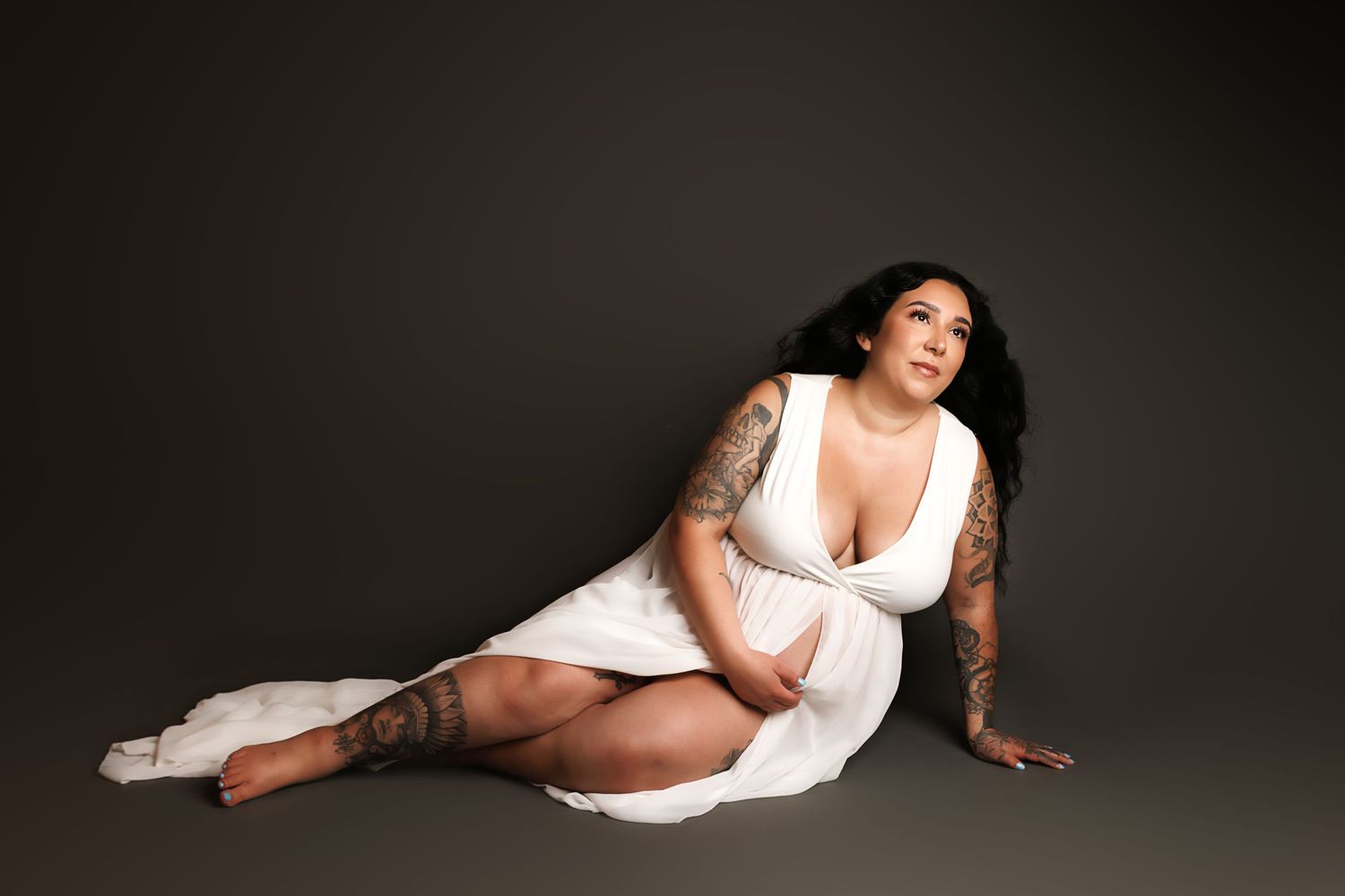 A figure in a white dress poses dramatically in a series of artistic boudoir portraits against a dark background.
