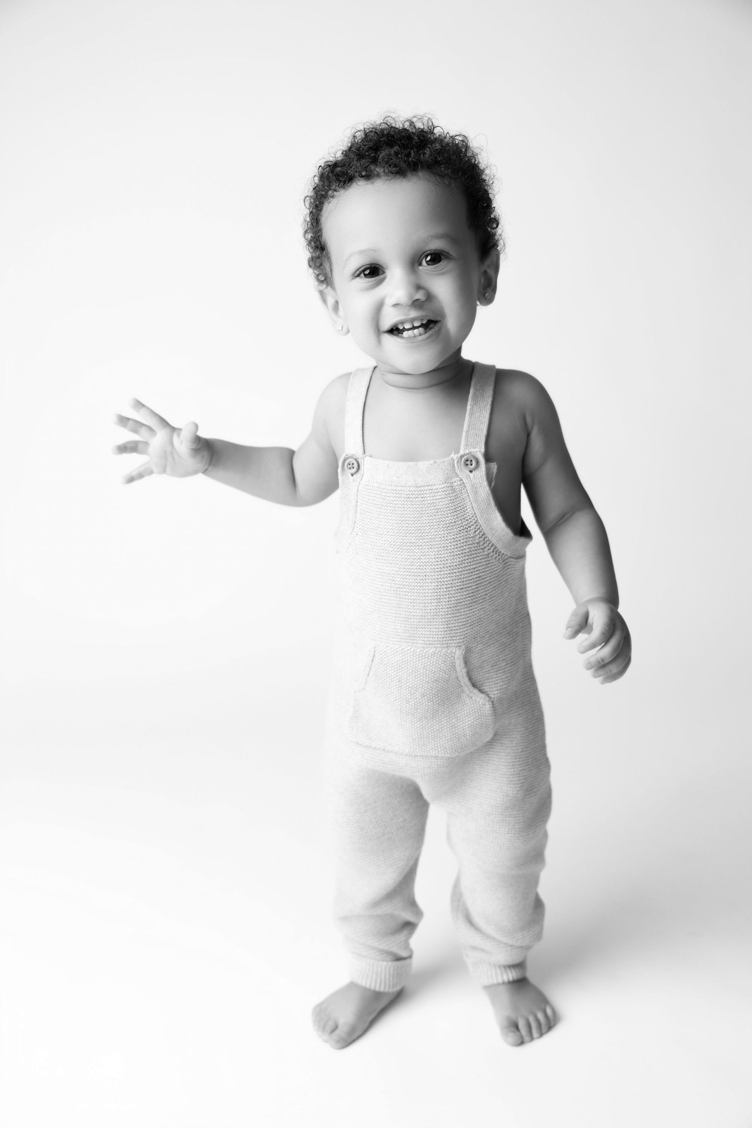 Black and white photo series of a joyful baby wearing a light-colored romper in various playful poses against white background.