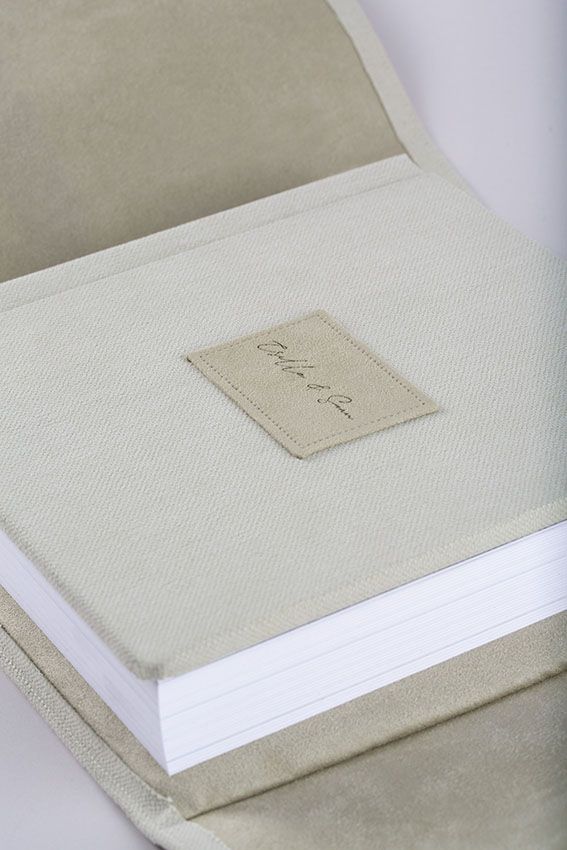 A series of minimalist white linen photo albums or books with subtle fabric textures and simple design details.