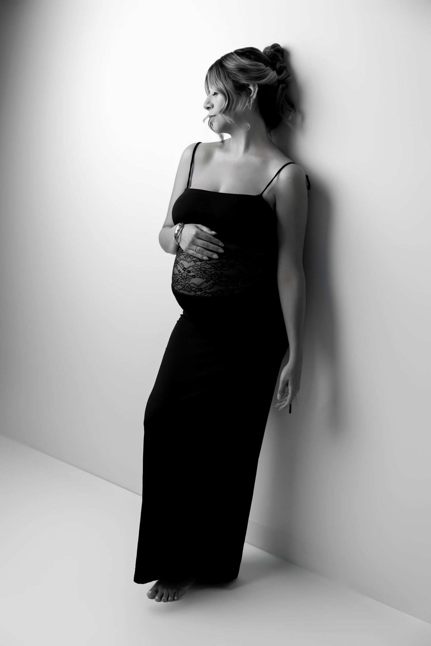 Artistic black and white portrait series showing a figure in a dark dress against a white wall with dramatic shadows.