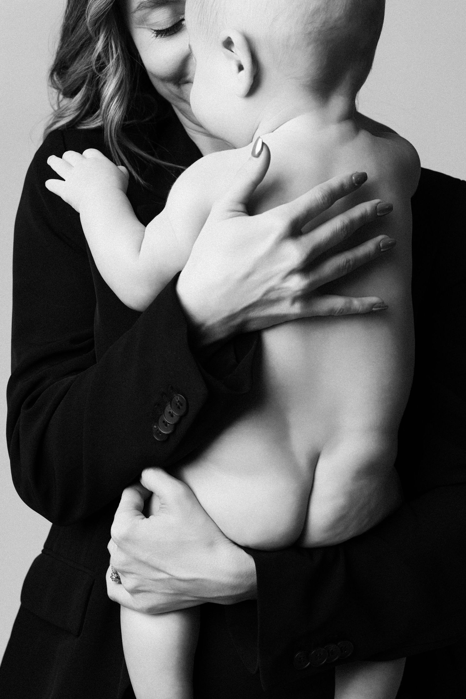 Artistic black and white photograph showing intimate embrace between two figures with dramatic shadows and contrast.