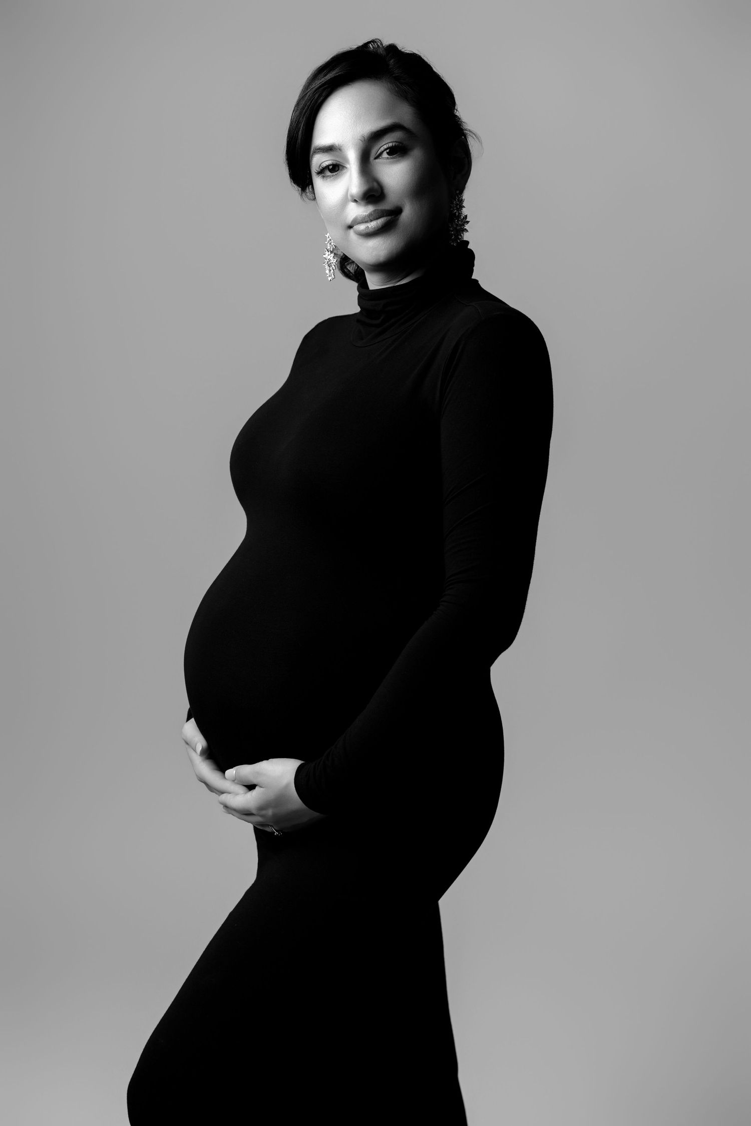 Minimalist black and white maternity portraits showing profile poses in dark turtleneck.