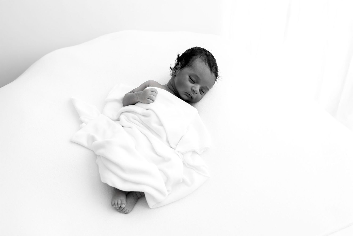 A person sleeping peacefully in white bedding against a soft pillow.
