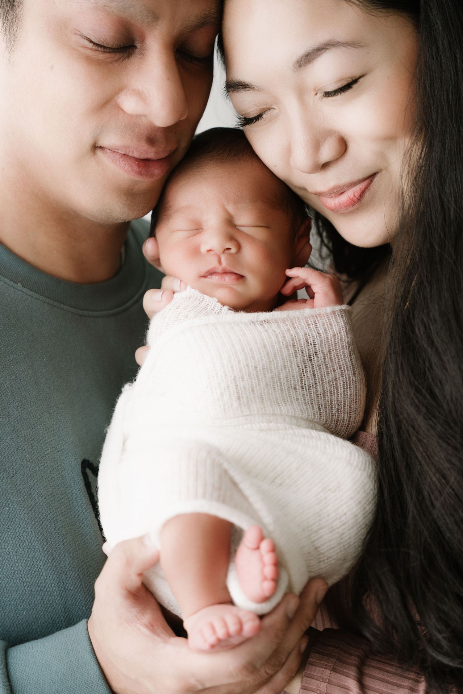 Intimate newborn family portrait with soft neutral tones showing tender moments of bonding.