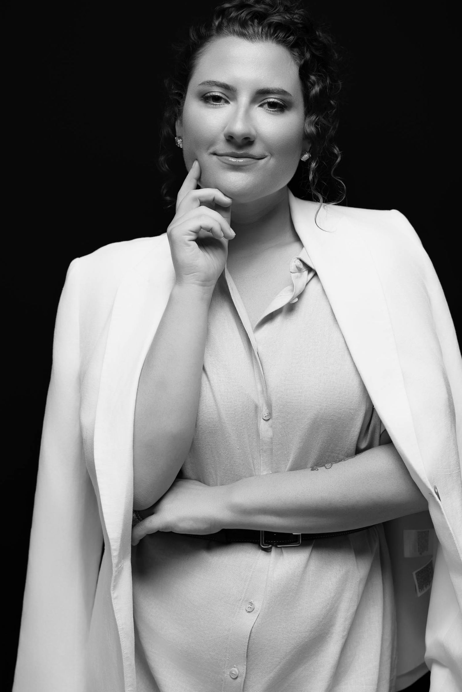 Elegant portrait series in white blazer and blouse against dark background.