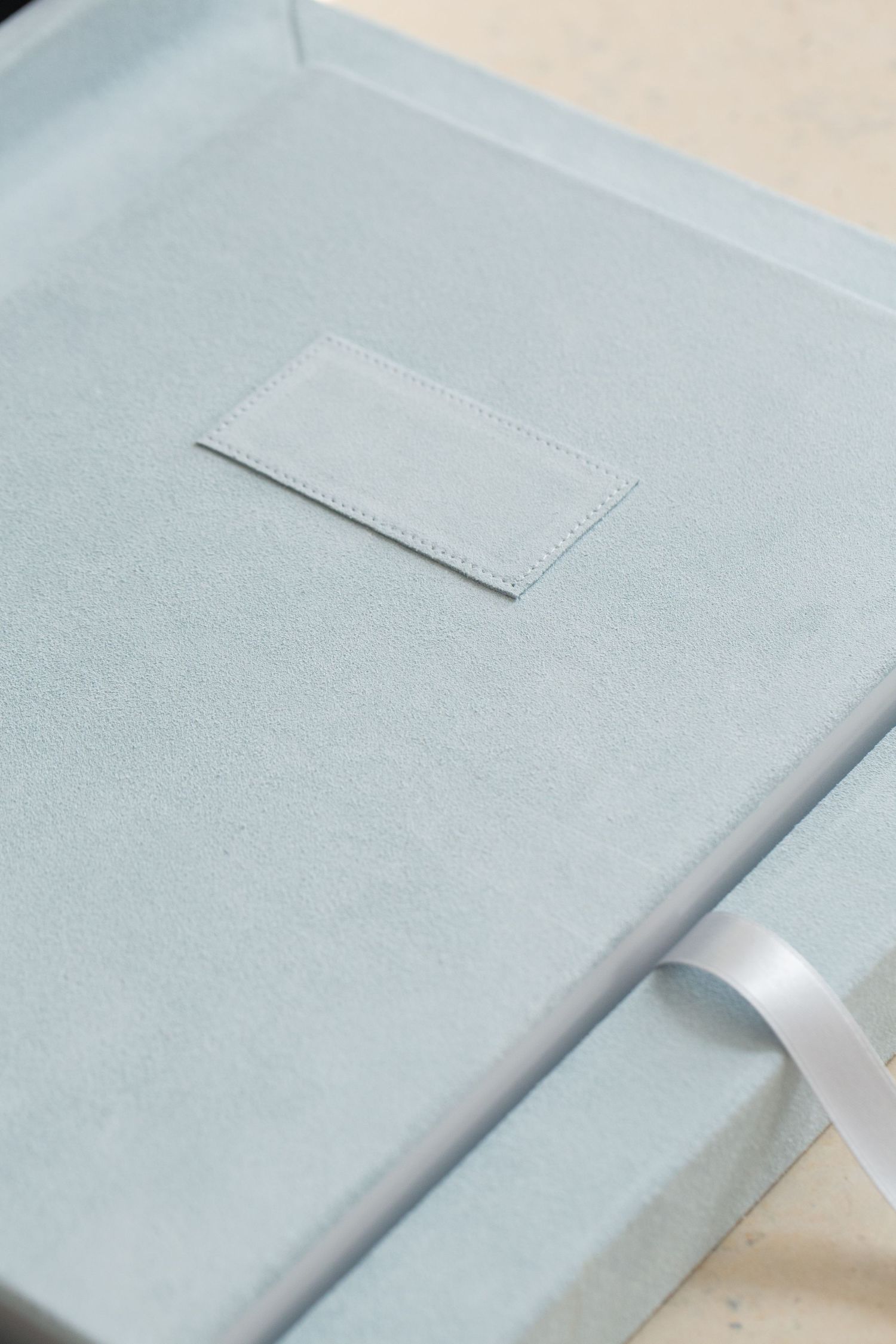 Light gray textured fabric surface with subtle stitched detail.
