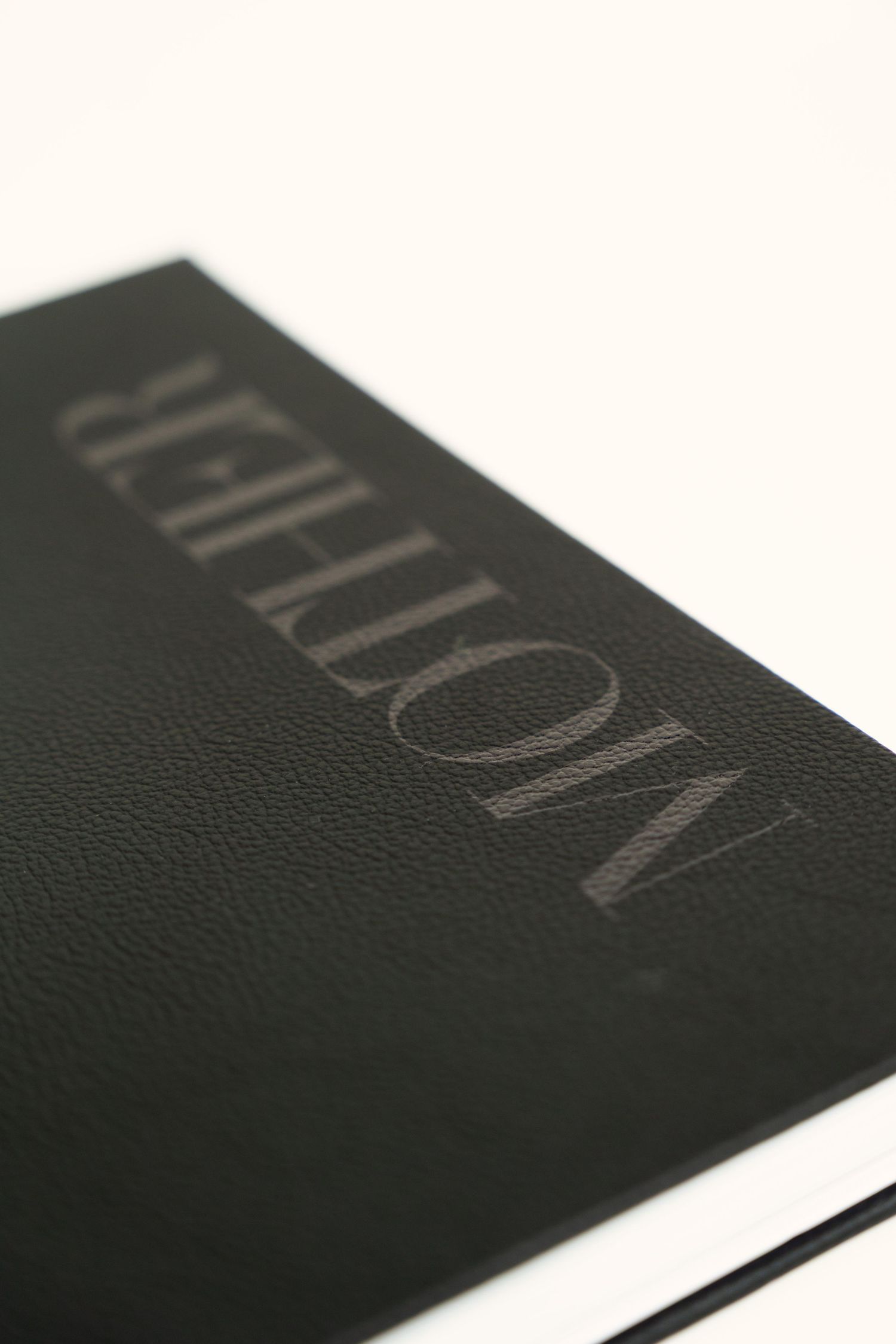 Detailed macro shot of black leather album cover with embossed text.