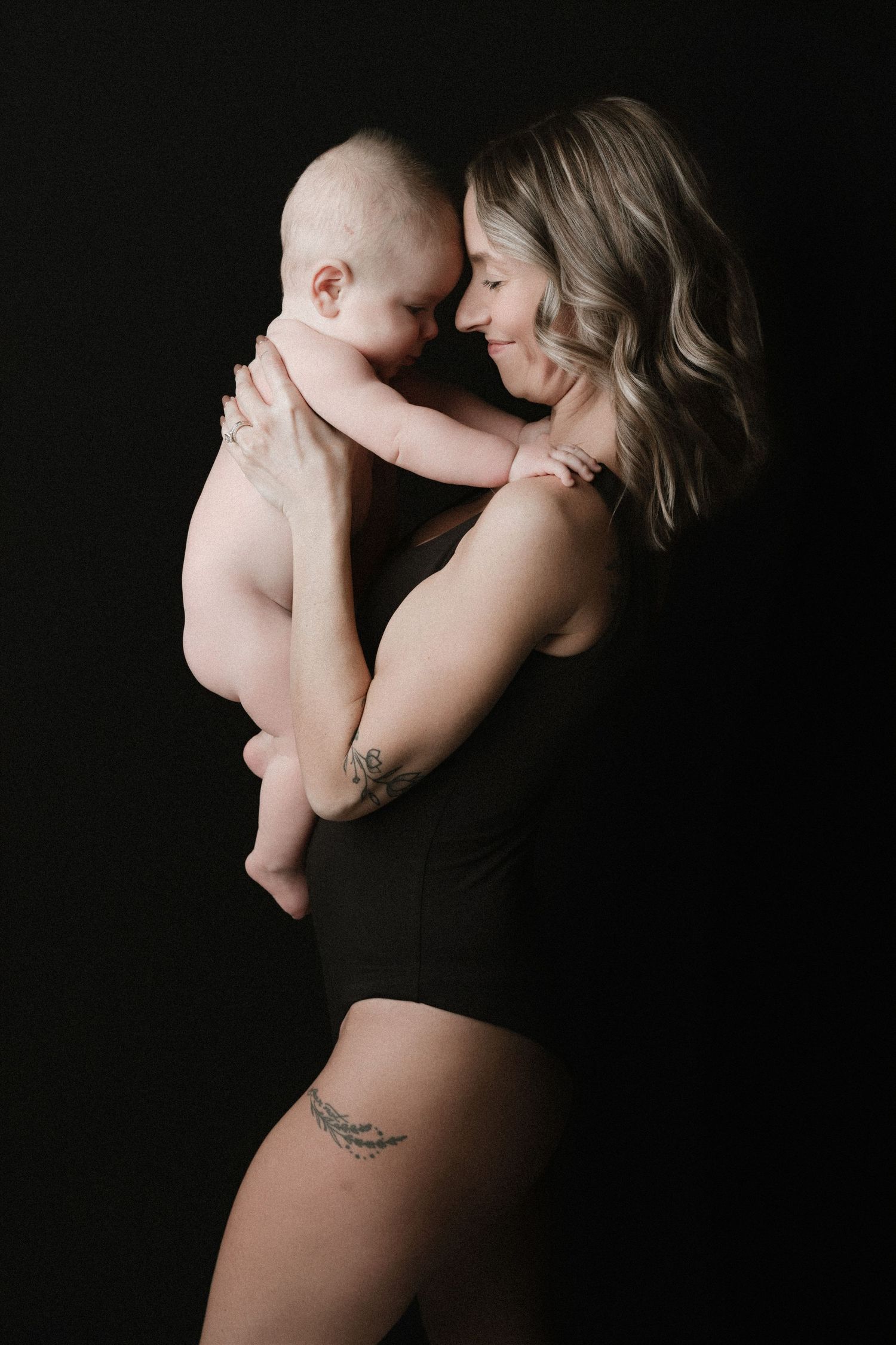 Artistic black and white maternity photography series showing intimate side profile poses against dark background.