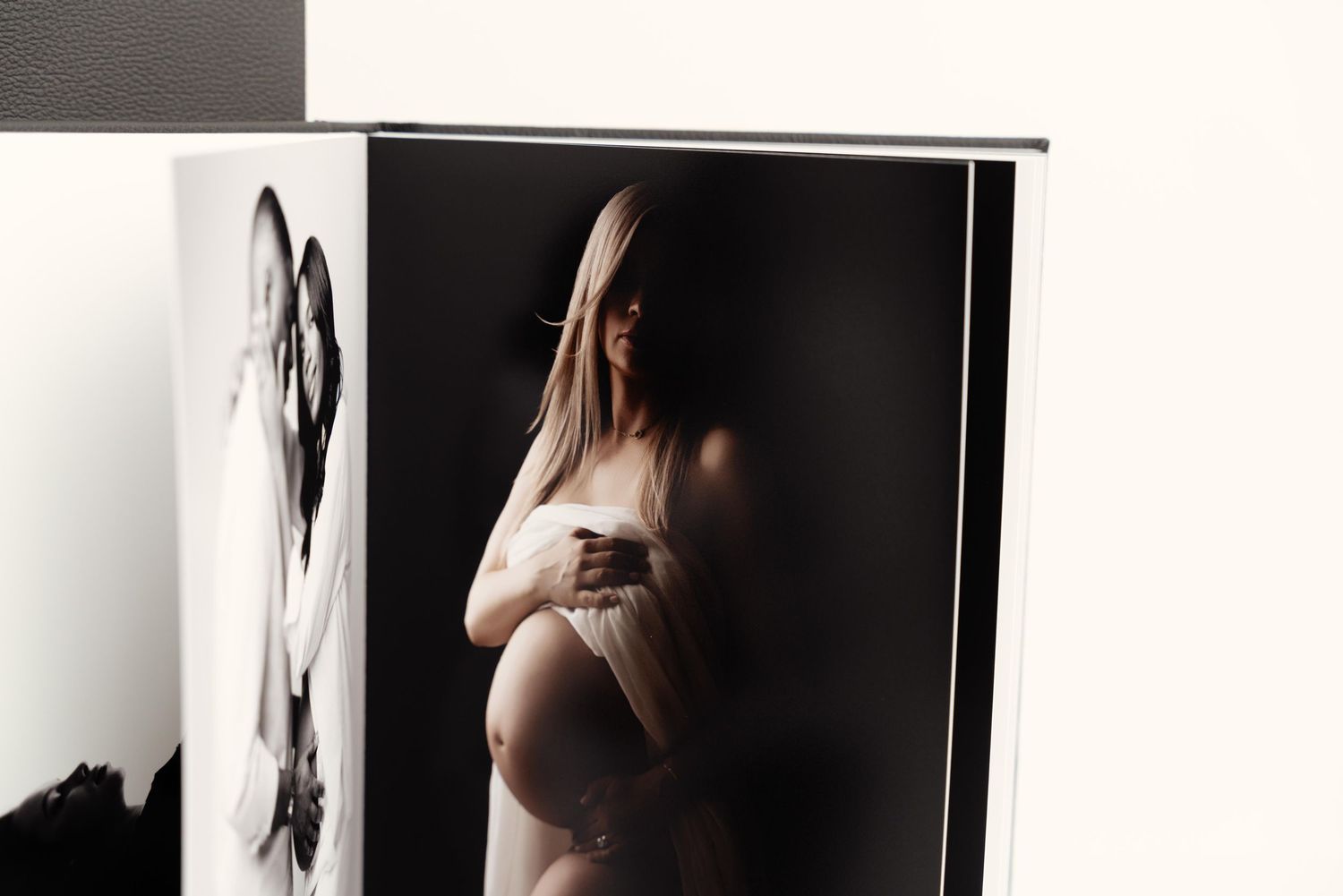 Artistic black and white maternity photoshoot showing silhouetted figures against a light background.