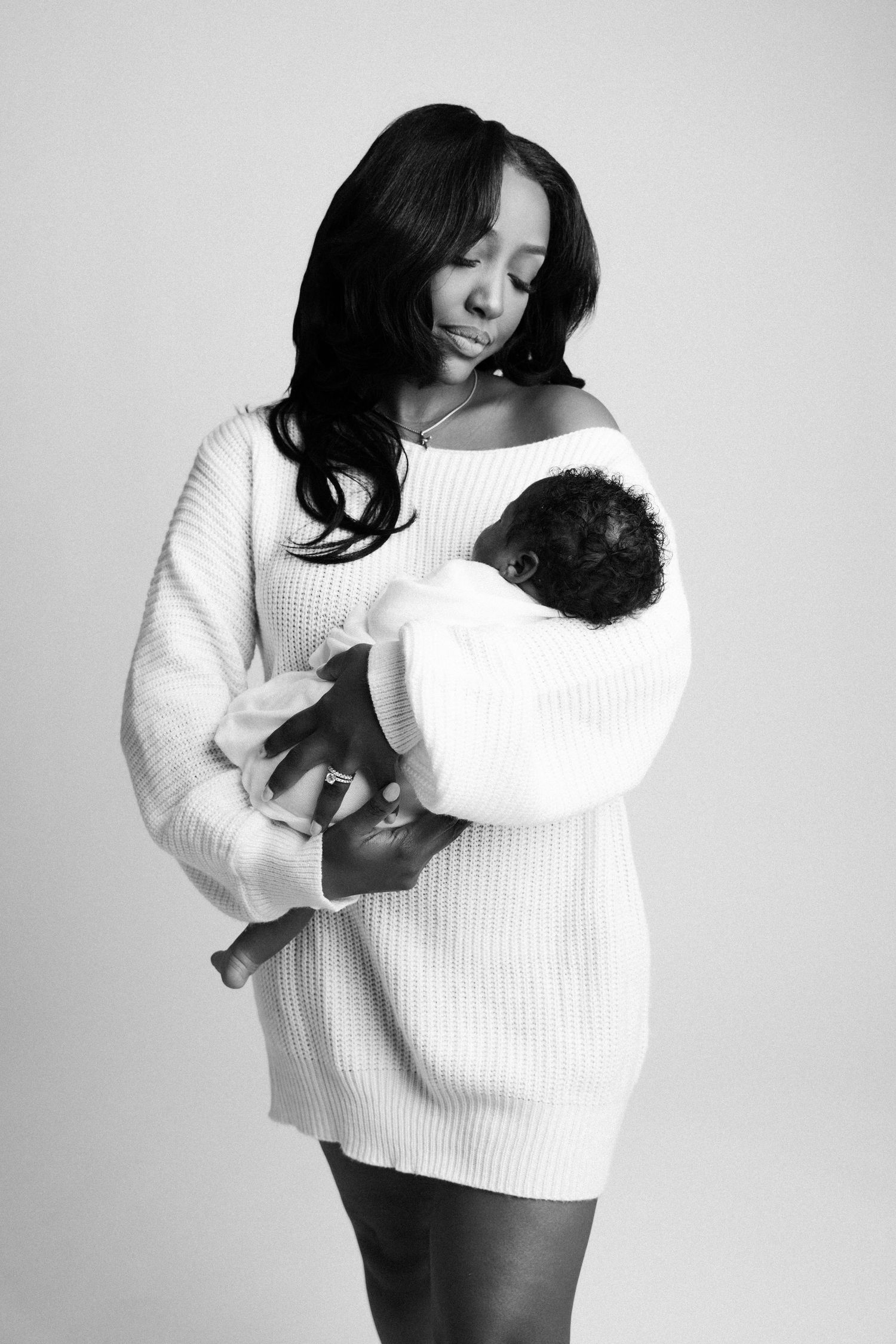 Black and white photo series of a person in a white sweater holding and embracing a small black cat.